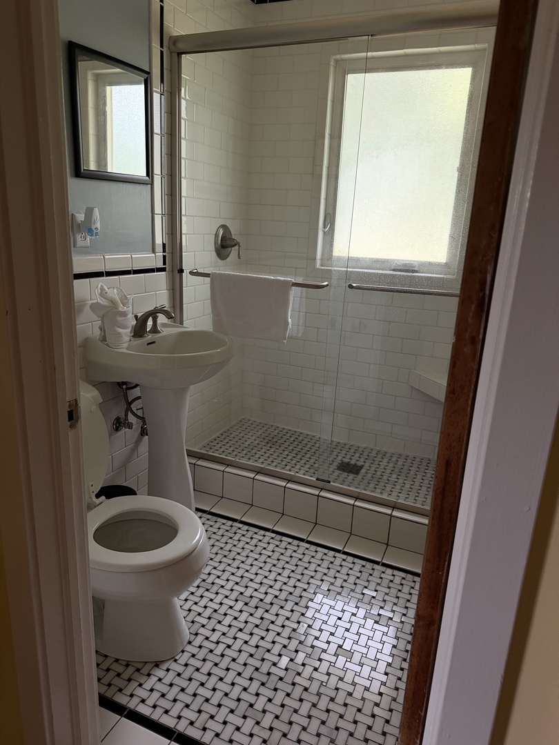Your private bathroom features classic white tile, a spacious walk-in shower, and plenty of natural light to start your day feeling refreshed.