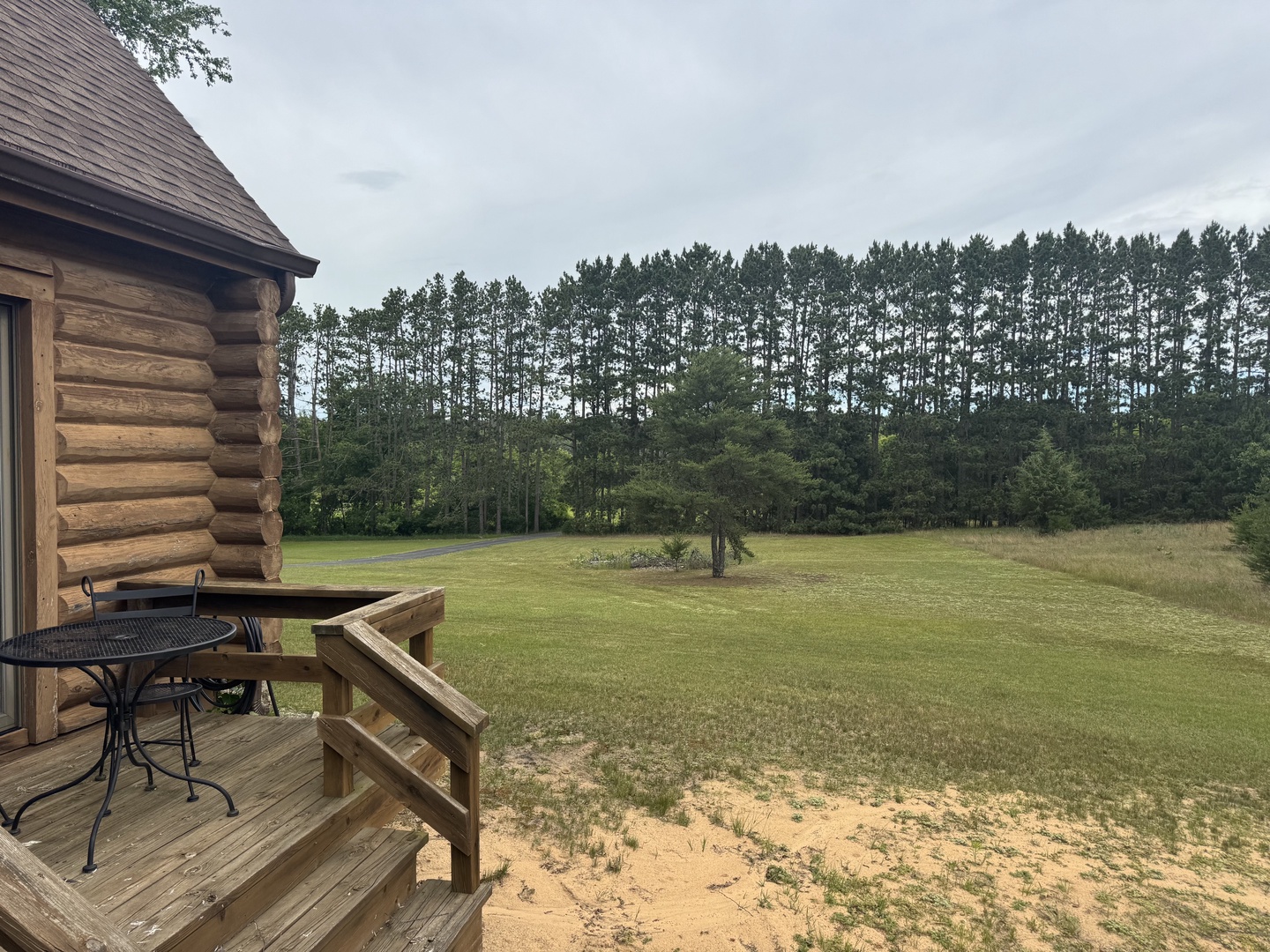 Rustic log cabin nestled beside a sprawling lawn and towering pines, offering peaceful seclusion surrounded by natural beauty.