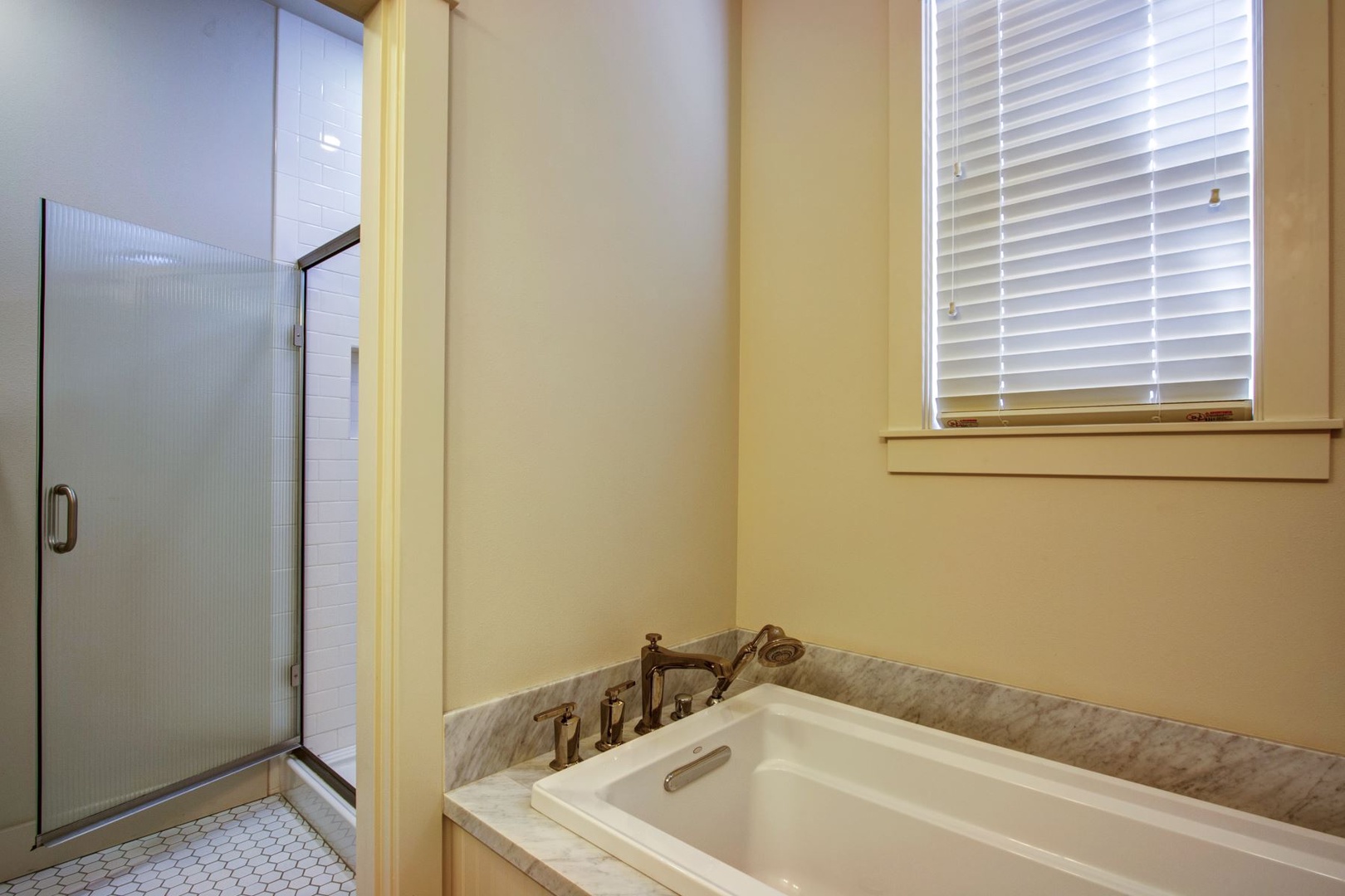 King primary bath with heated floors, walk in shower and a marble bath tub