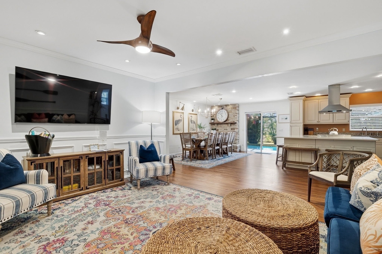 Relax in this spacious open-concept living area where comfortable seating, warm wood floors, and natural light create the perfect gathering space for your group.
