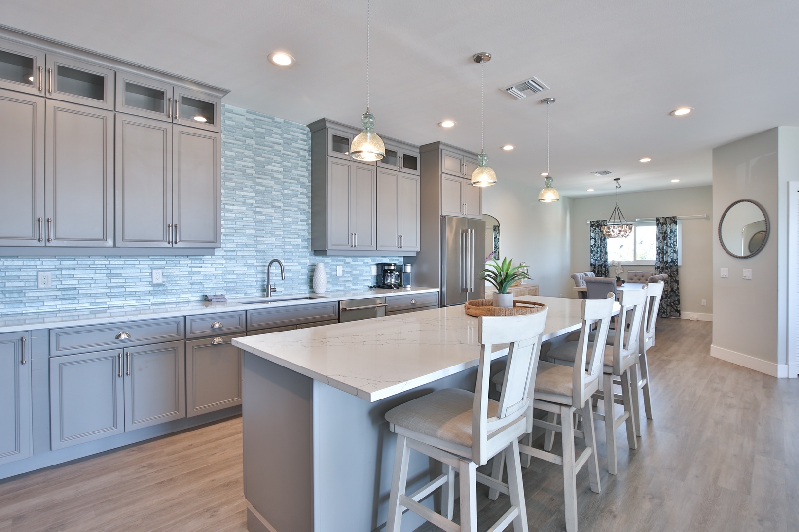 Your gourmet kitchen awaits with sleek gray cabinetry, stunning blue tile backsplash, and spacious island seating for memorable meals together.