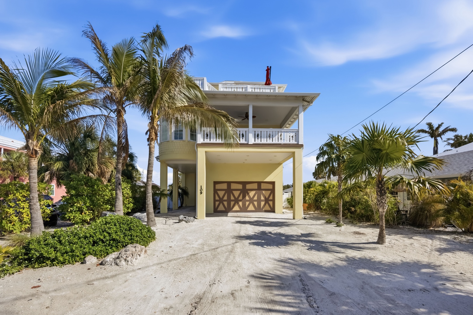 Charming two-story coastal home with tropical landscaping and covered parking in a peaceful island neighborhood.