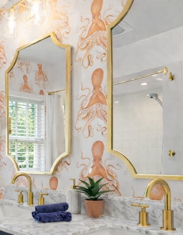 Immerse yourself in this whimsical bathroom featuring playful octopus wallpaper, elegant gold fixtures, and marble surfaces that create a luxurious coastal retreat.