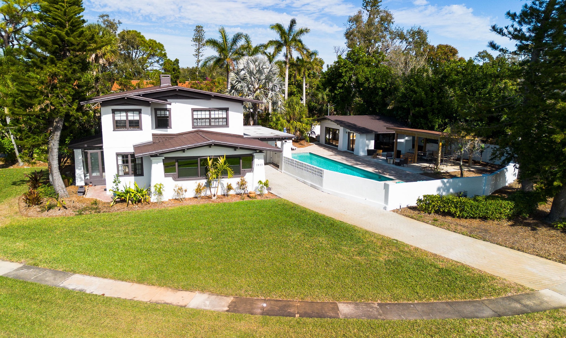 Modern coastal retreat featuring spacious grounds, sparkling pool, and lush tropical landscaping in a peaceful residential setting.