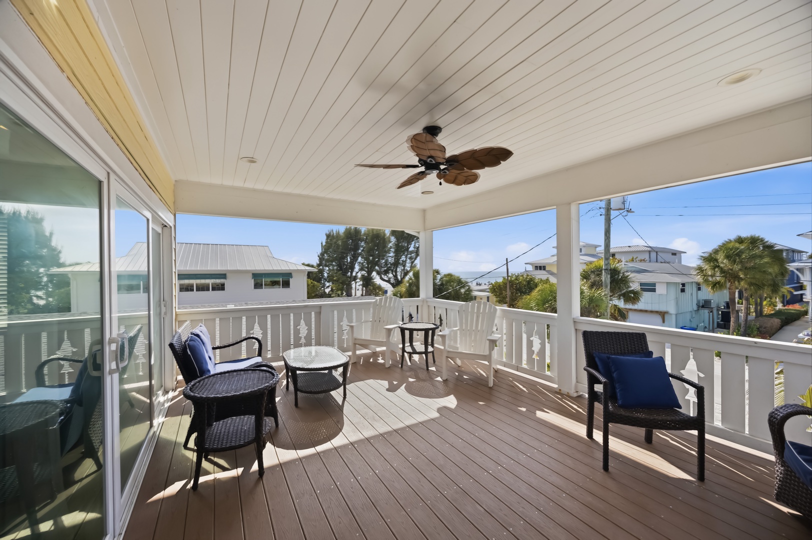 Your private covered balcony with comfortable seating and ceiling fan offers the perfect spot to unwind while enjoying tropical neighborhood views.