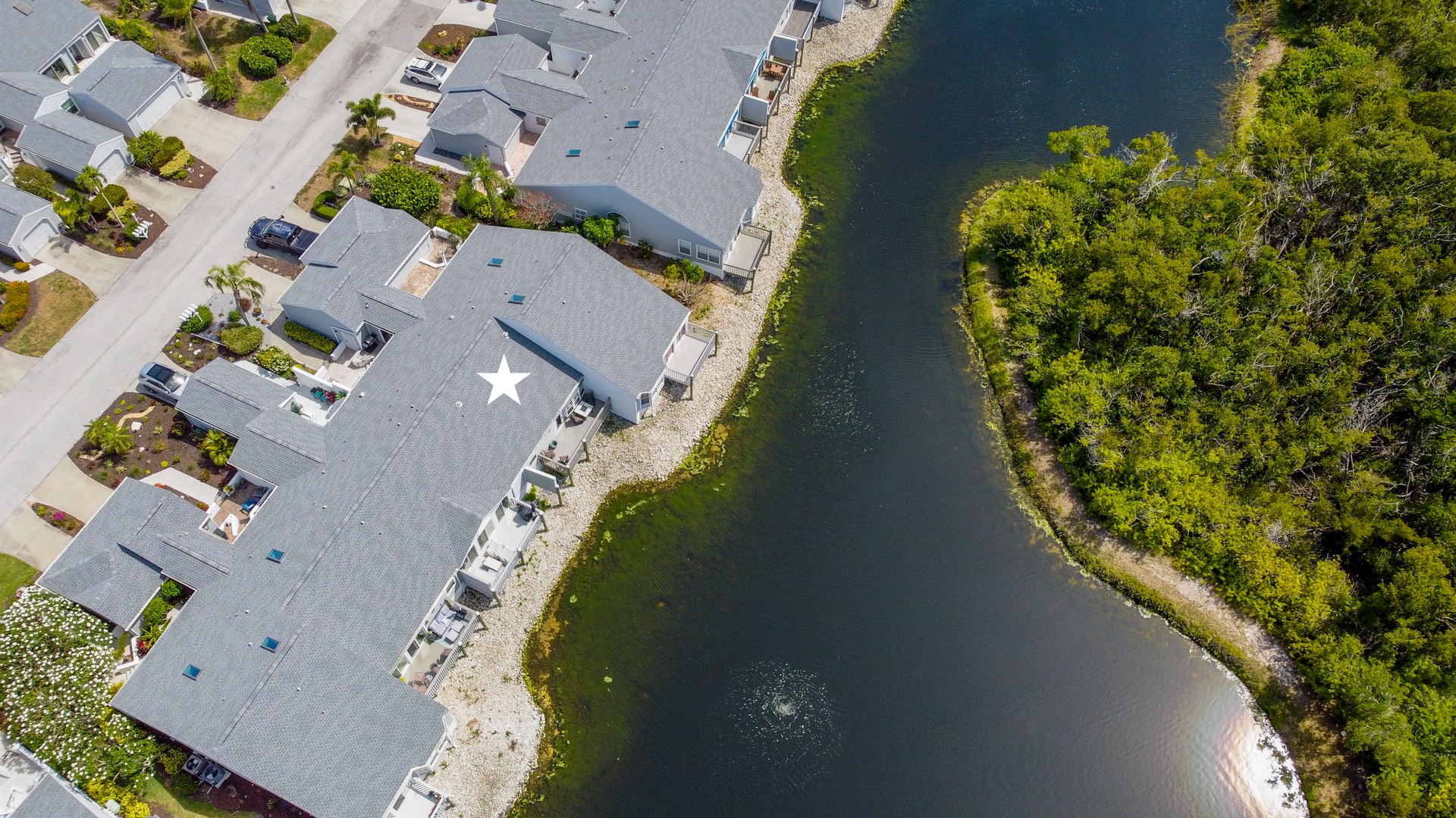 Aerial view of waterfront vacation homes nestled along a serene river, surrounded by lush greenery and featuring peaceful natural surroundings.