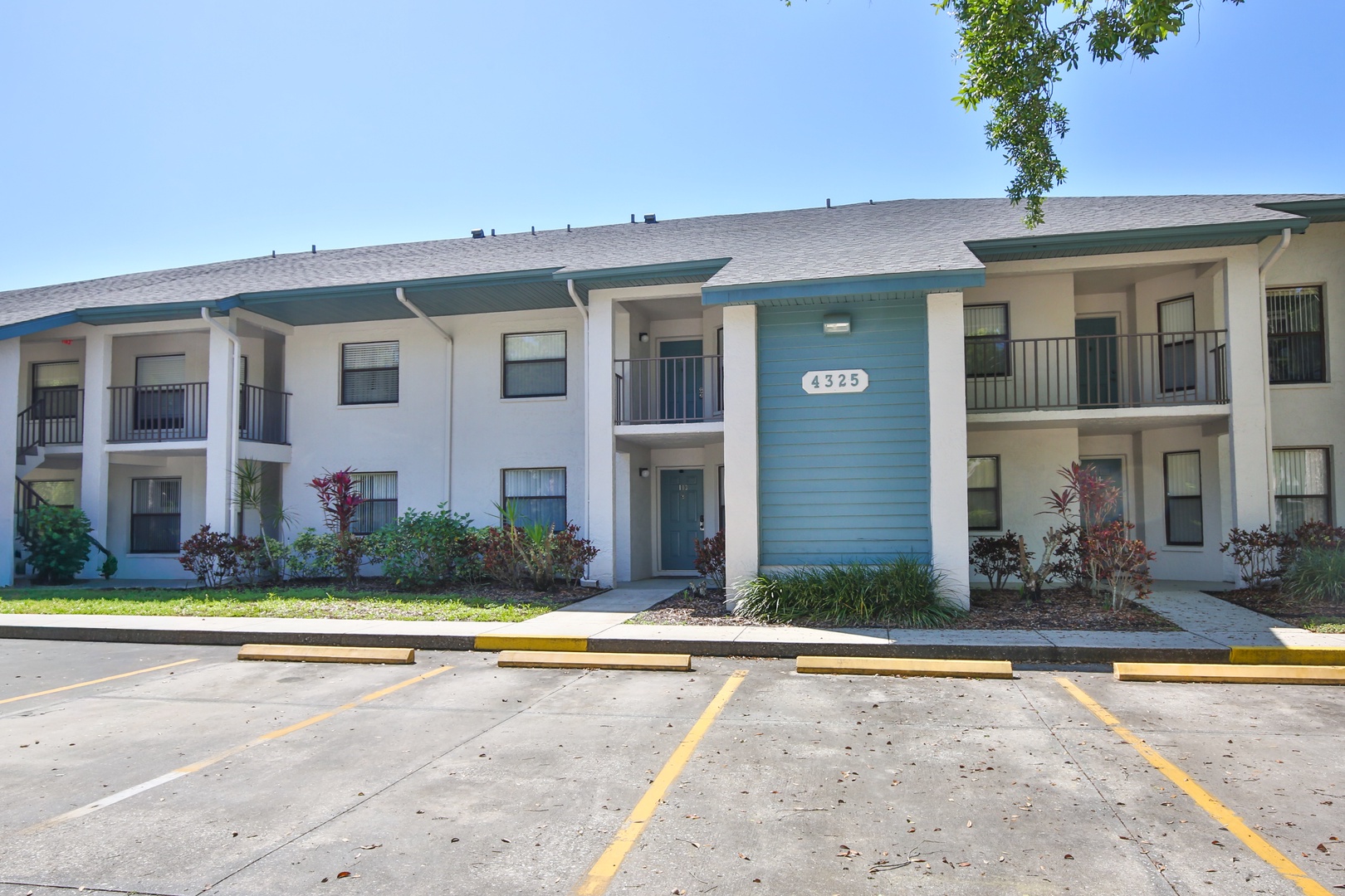 Two-story apartment building with blue and white exterior featuring multiple units and convenient parking spaces.