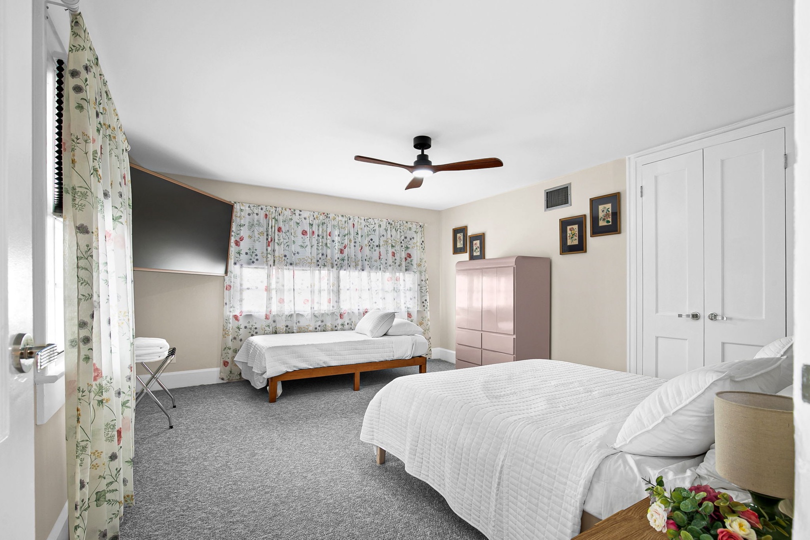 Sleep peacefully in your spacious twin bedroom with crisp linens, cheerful botanical curtains, and gentle ceiling fan creating the perfect restful retreat.