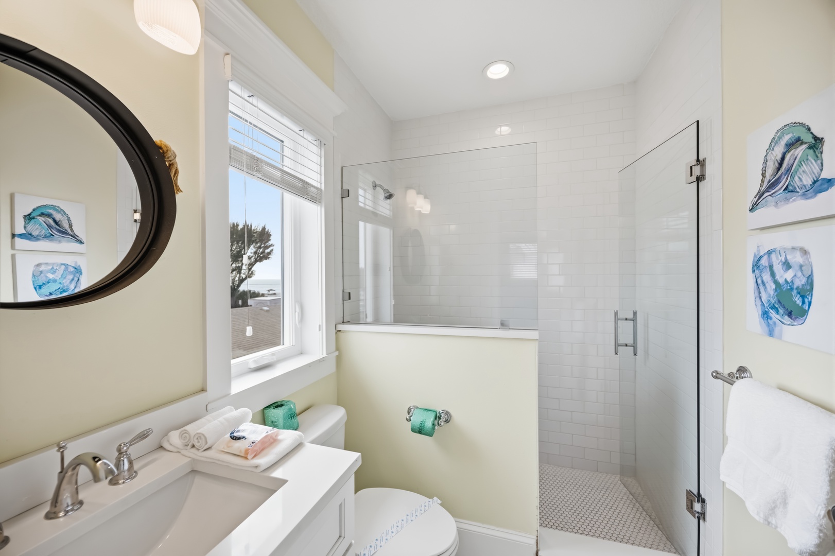 Step into your bright, coastal-themed bathroom featuring a glass-enclosed shower, elegant vanity, and cheerful artwork that sets a perfect seaside mood.