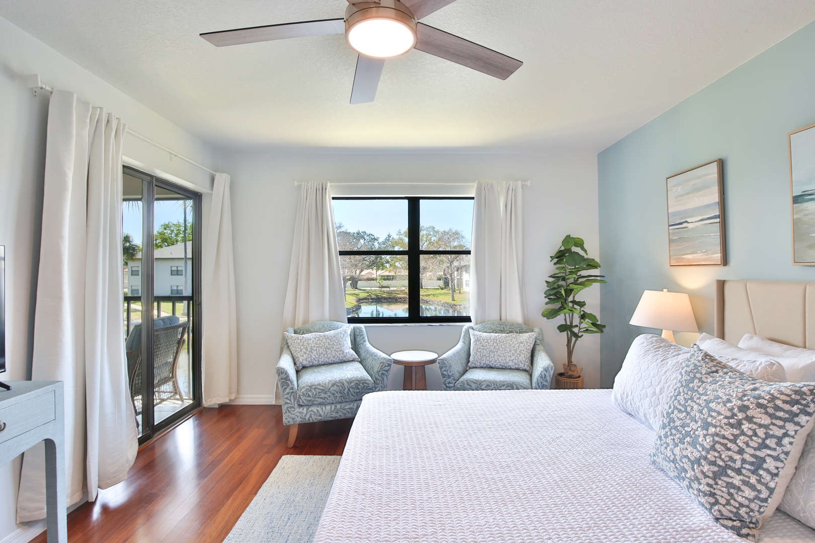 Drift off in your serene bedroom featuring a cozy seating nook by the window and soothing coastal colors that invite relaxation.