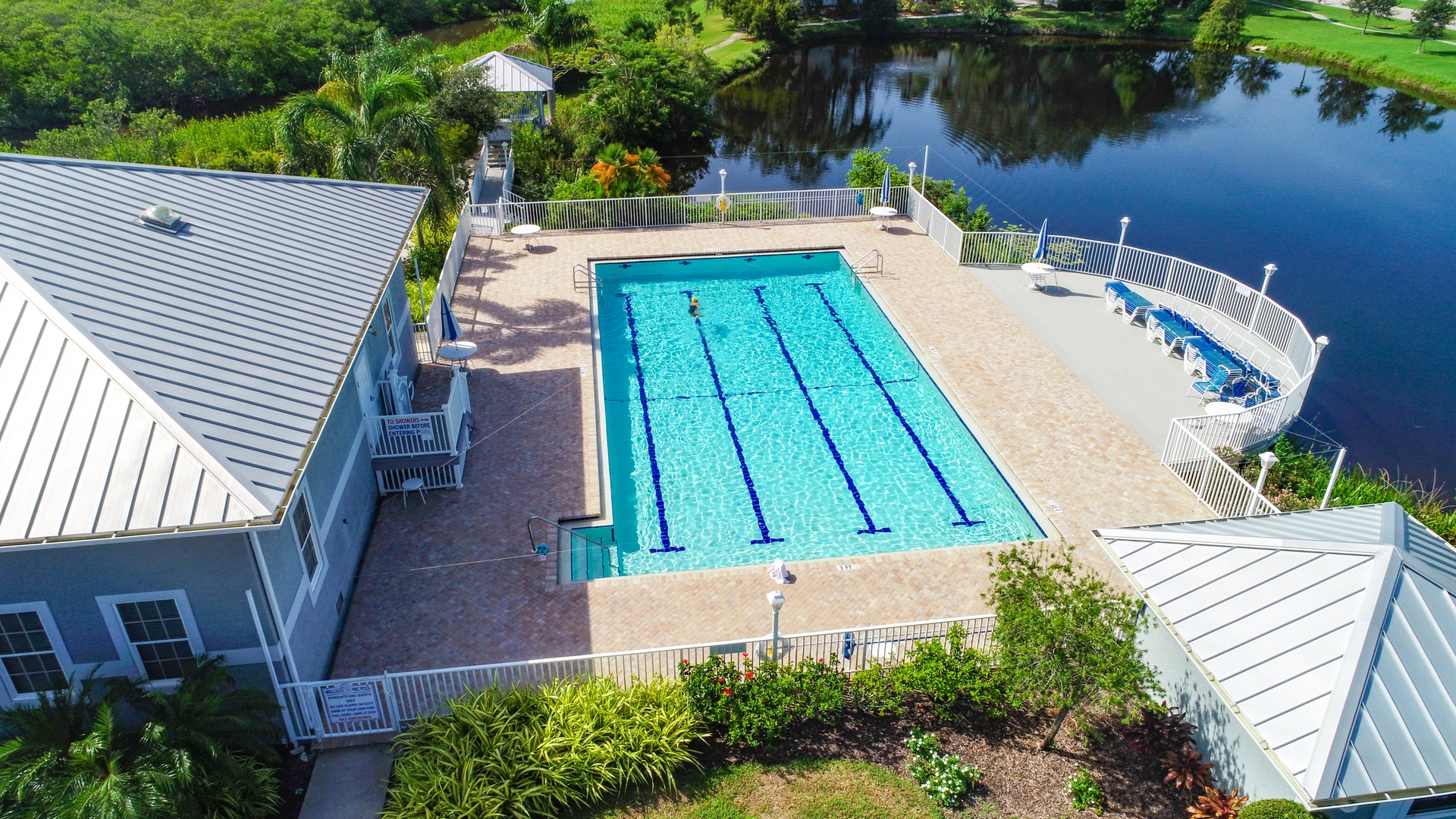 Aerial view of the property's lap pool and lakefront setting, with manicured grounds and scenic surroundings ideal for a peaceful retreat.