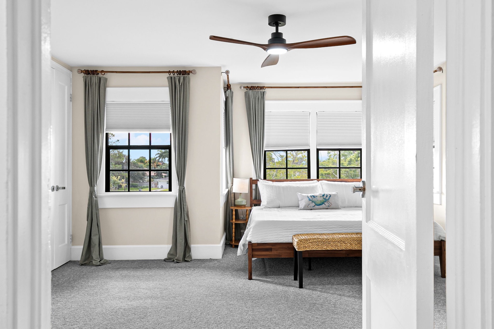 Step into your serene bedroom retreat, where crisp white linens and a gentle ceiling fan create the perfect atmosphere for restful nights.