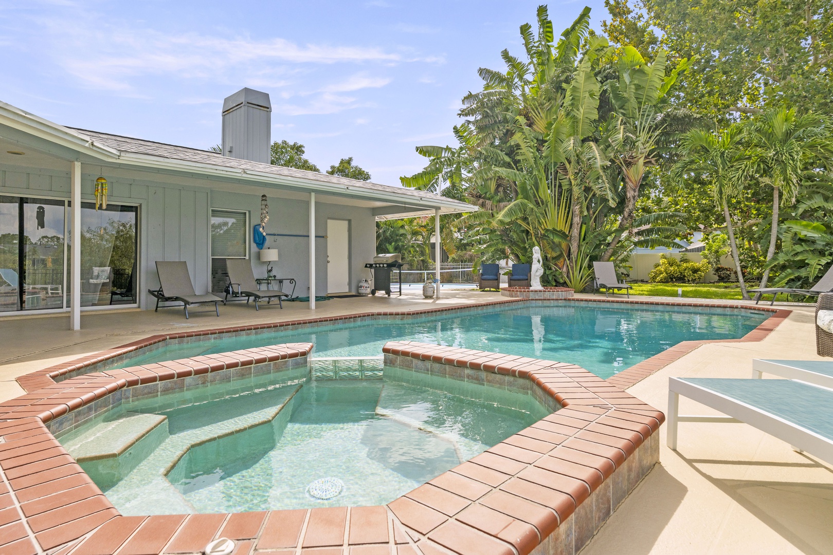 Your private oasis awaits with a sparkling pool and soothing spa, surrounded by lush tropical palms. Relax on loungers under covered patio space, fire up the grill, and soak in the sunny serenity of your backyard retreat.