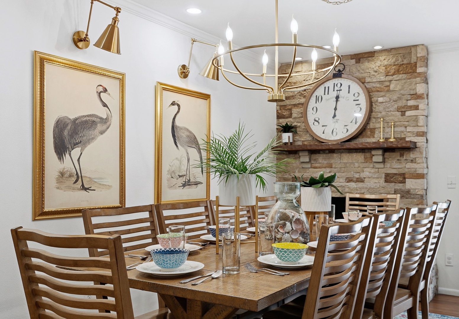 Gather around your elegant dining table for memorable meals beneath the warm glow of brass fixtures and charming bird artwork.