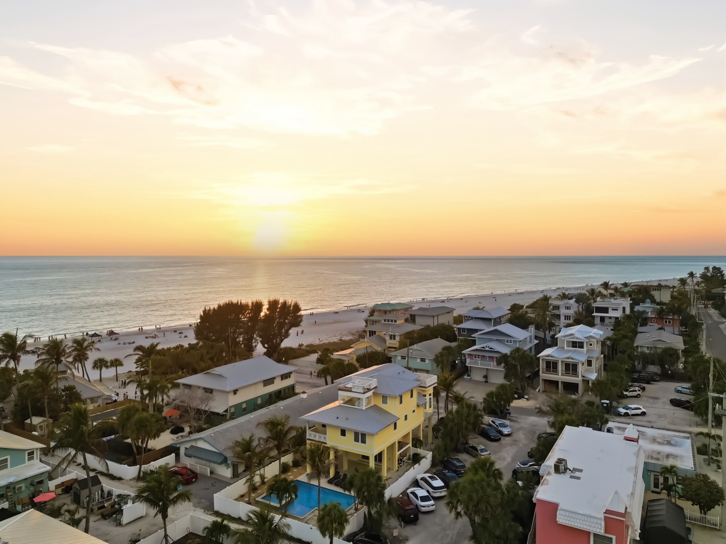 Golden sunset paints the sky over this charming beachfront community with sandy shores just steps away.