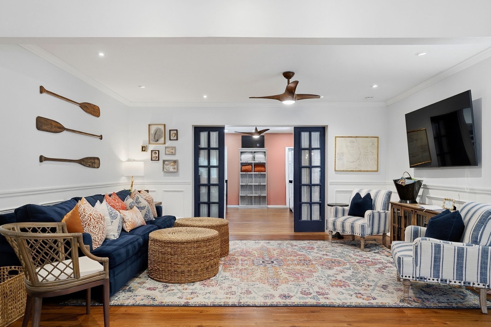 Relax in your coastal-inspired living room with navy seating, vintage oar decor, and warm hardwood floors beneath your feet.