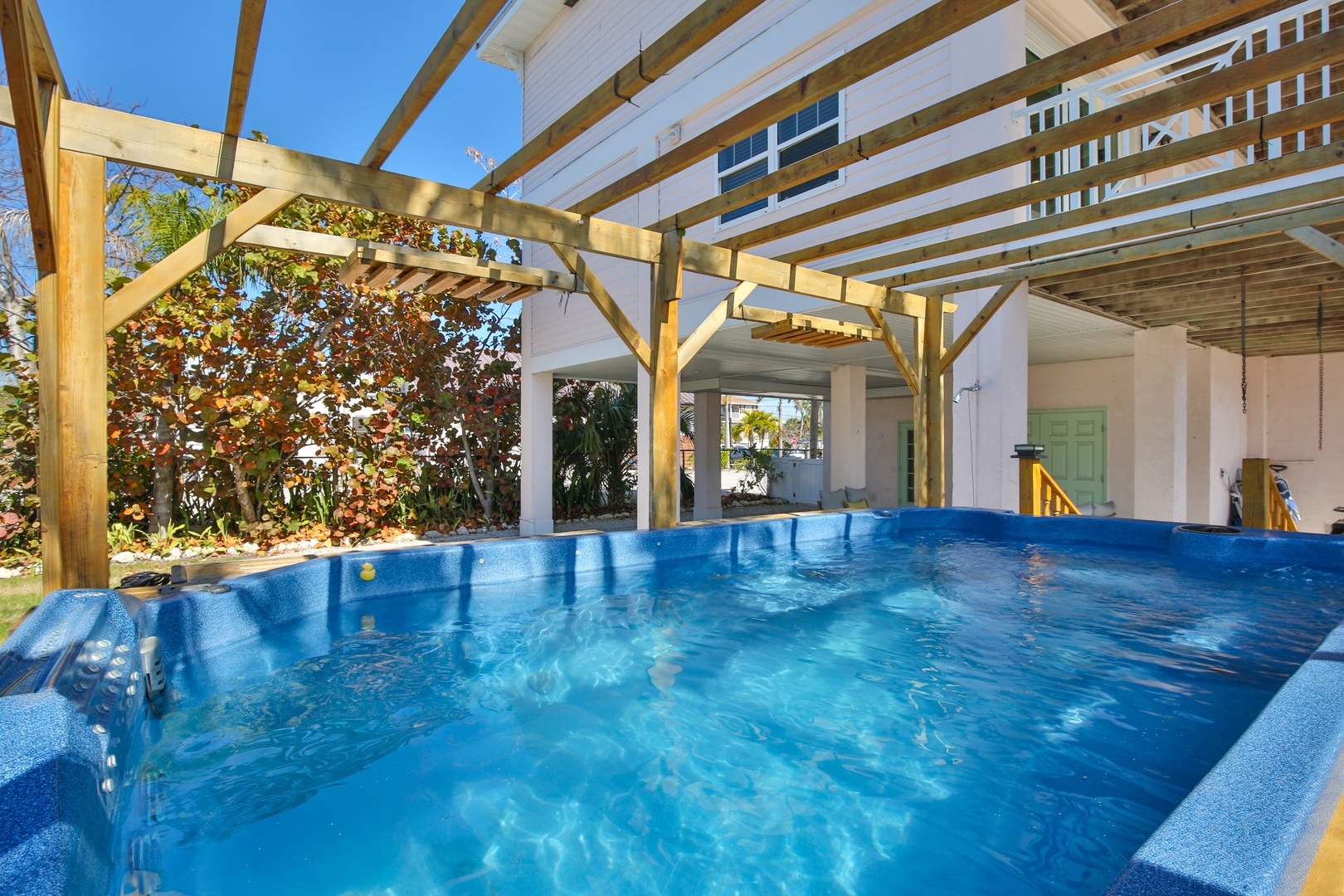 Dive into your private oasis with crystal-clear blue water and sunny wooden pergola overhead, perfect for relaxing swims.