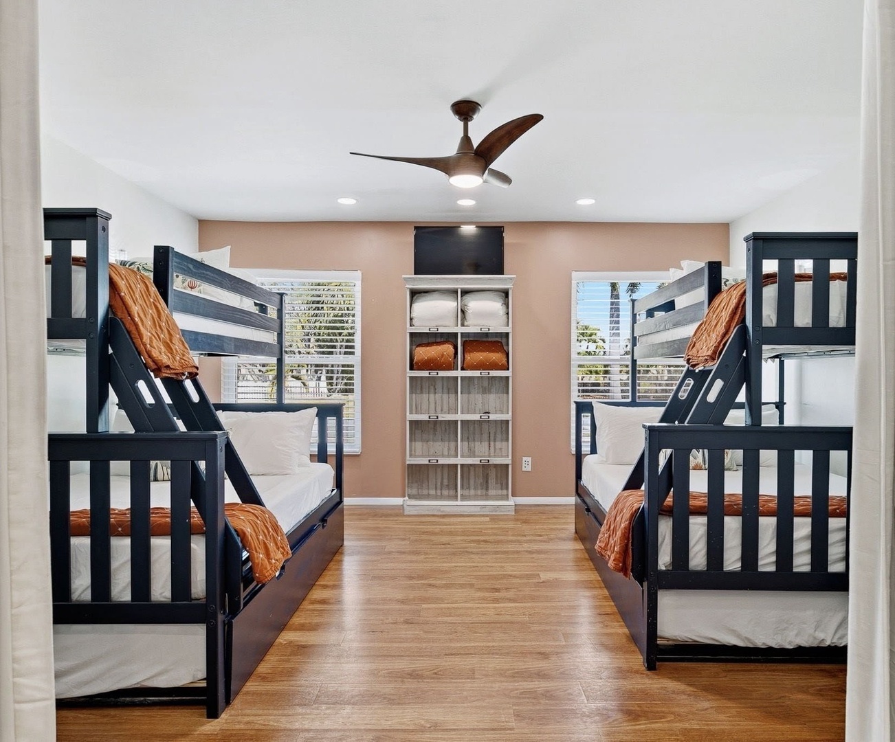 Your group can rest easy in this spacious bunk room with six comfortable beds, organized storage, and cheerful orange linens for a cozy night's sleep.