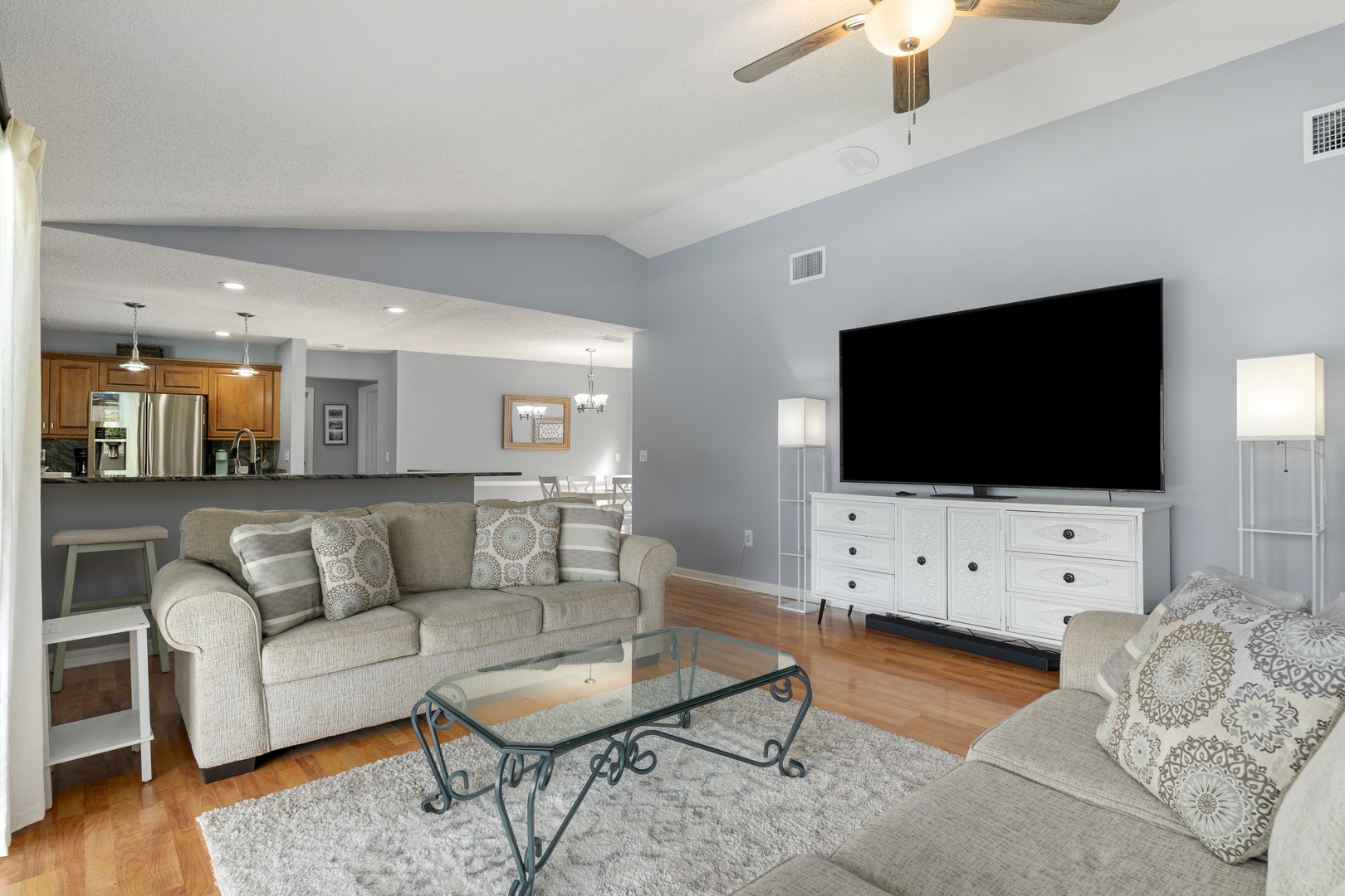 Cozy living area with neutral tones and soft textures flows seamlessly into a fully-equipped kitchen, perfect for preparing meals or enjoying relaxed conversation.