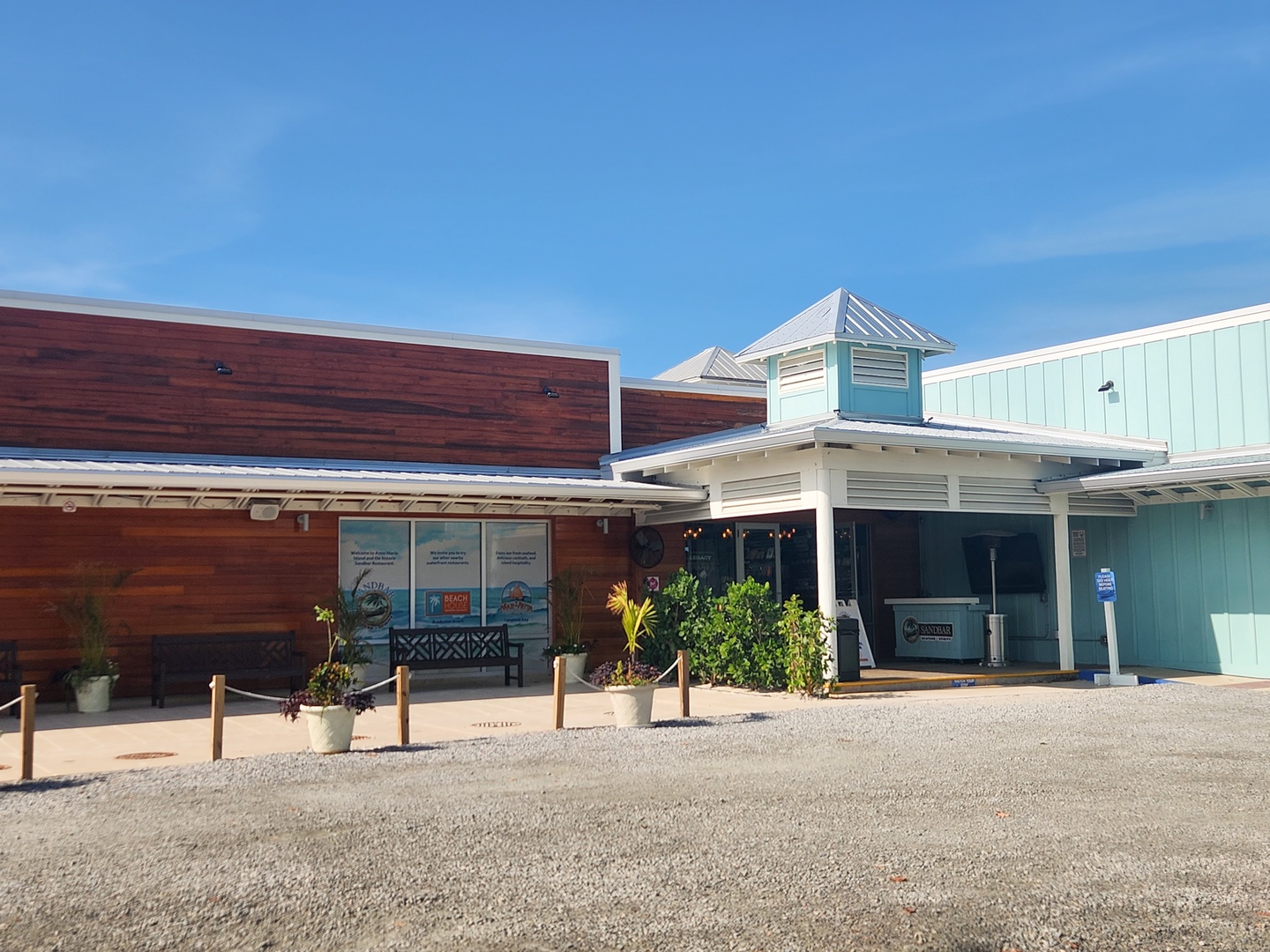 Modern beach-style building with distinctive wood and aqua siding under brilliant blue skies.