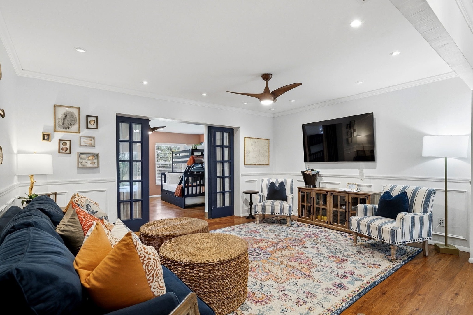 Sink into plush navy sofas and striped chairs in your elegant living space, where warm wood floors and coastal charm create the perfect retreat.