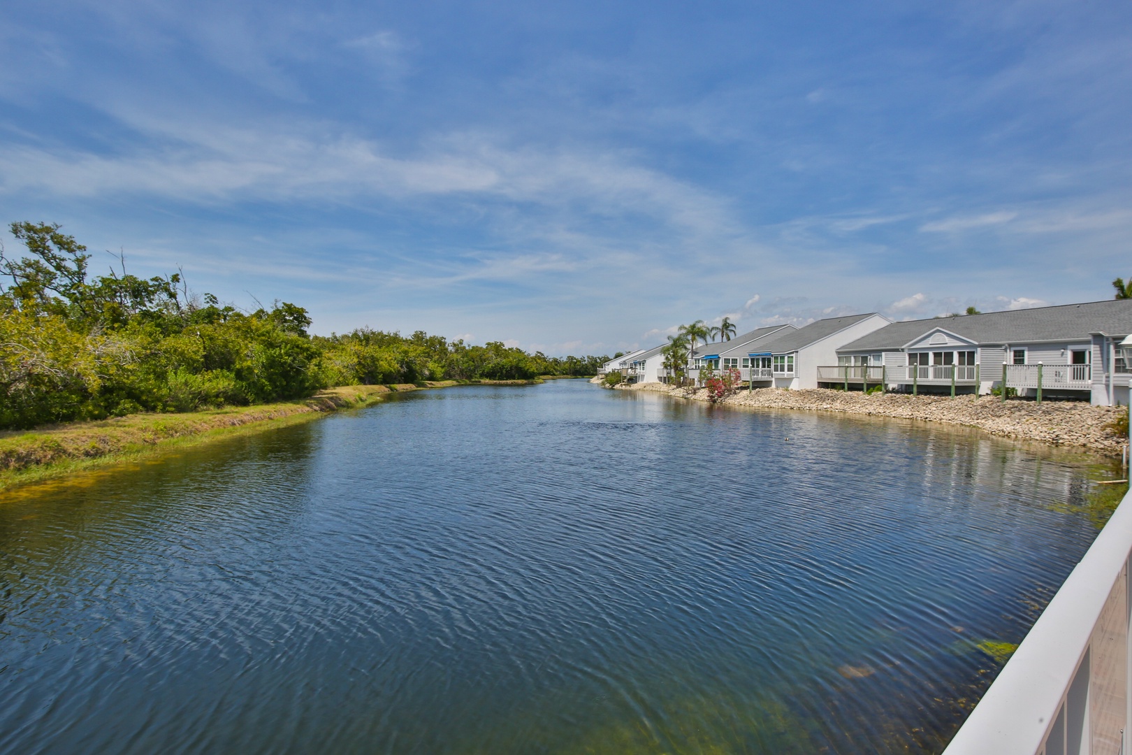 A peaceful canal winds through the neighborhood, bordered by lush greenery and waterfront homes, offering a tranquil setting for this vacation retreat.