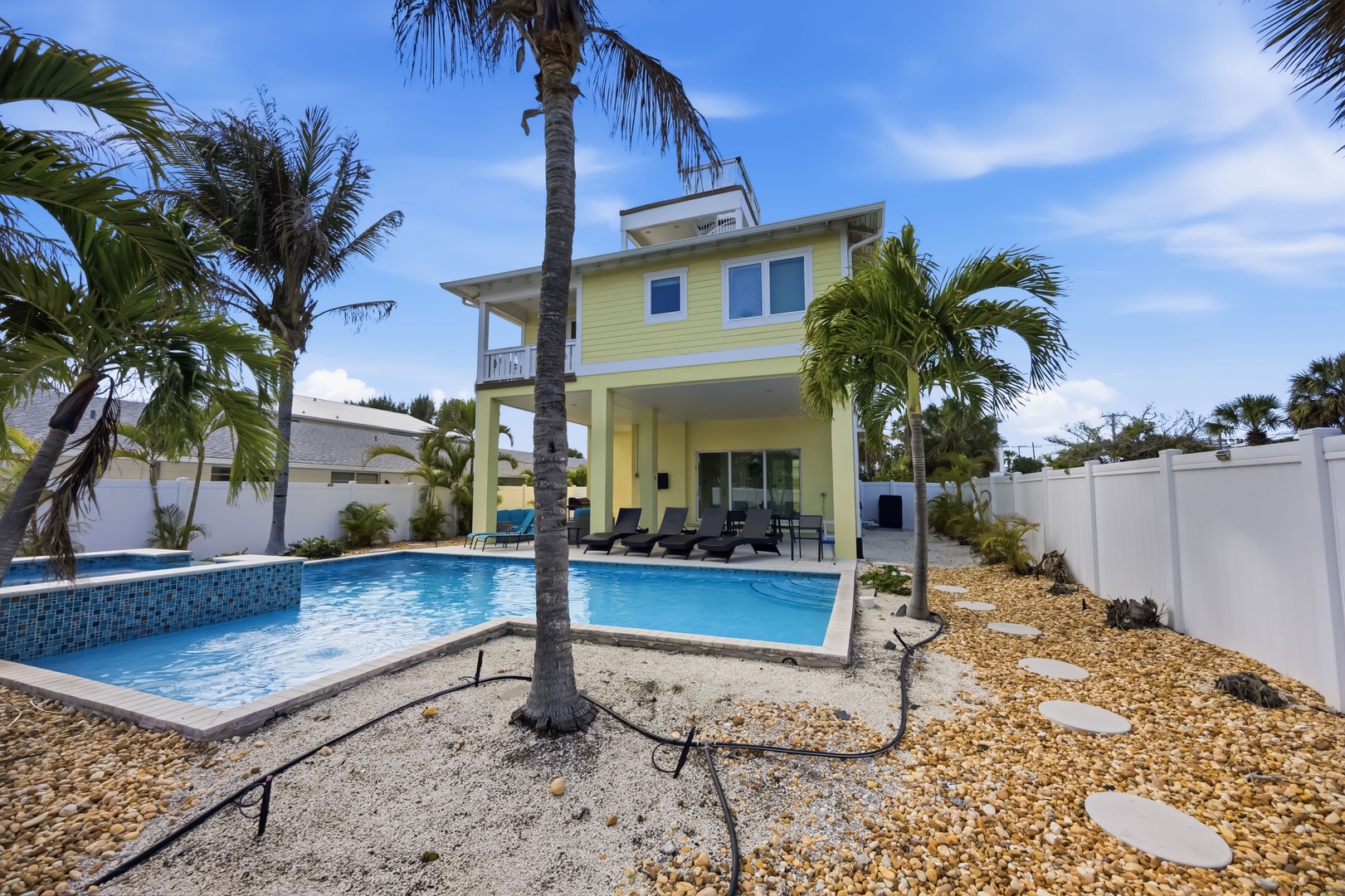 Modern tropical villa with private pool, surrounded by swaying palm trees and lush landscaping.