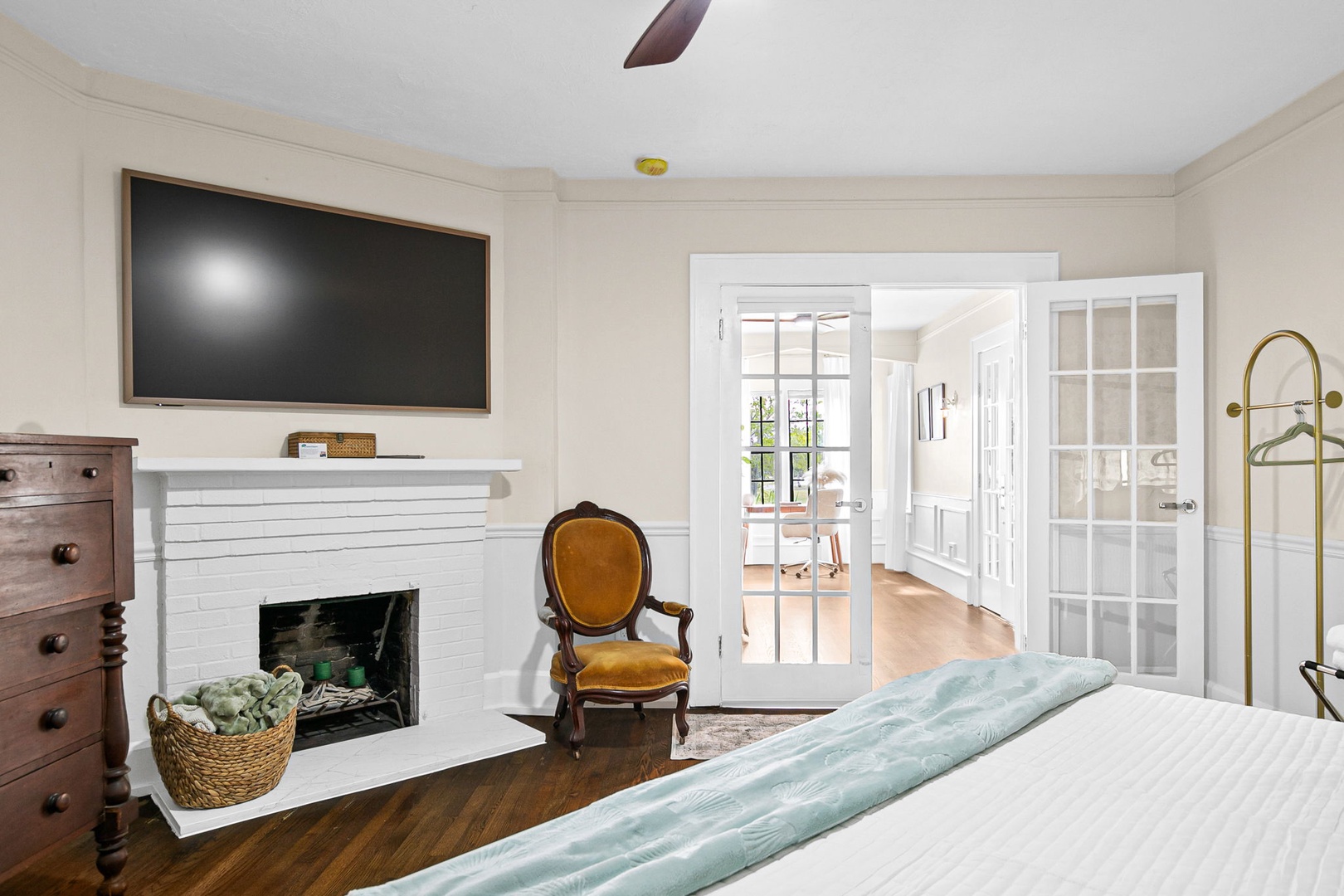 Unwind in your elegant master suite featuring a cozy fireplace, flat-screen TV, and charming French doors opening to bright spaces beyond.