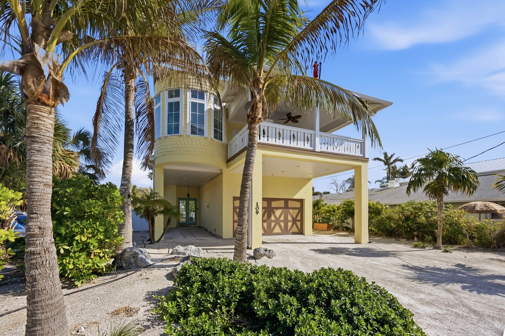 Tropical vacation home surrounded by swaying palms and lush landscaping in a peaceful island setting.