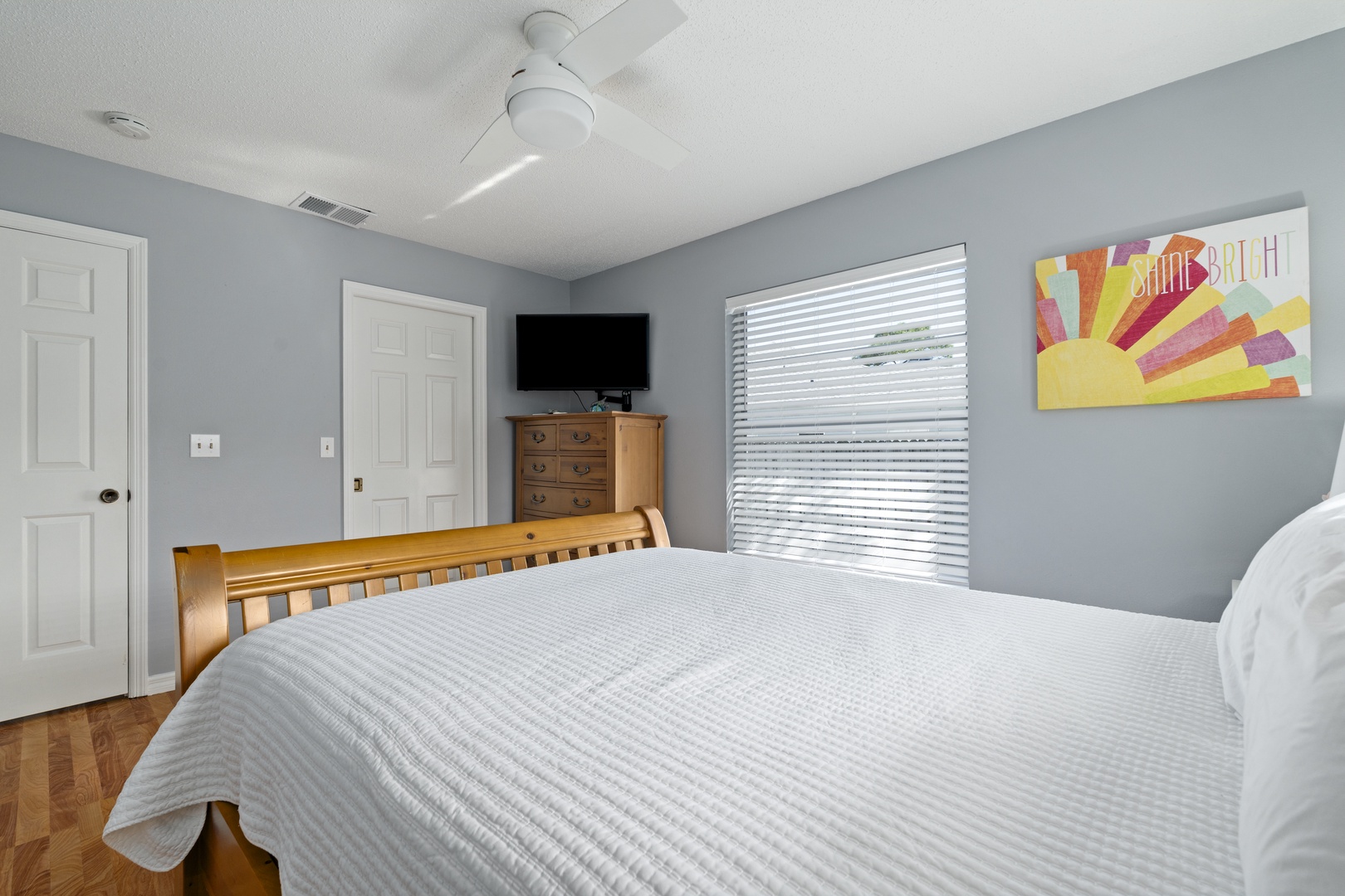 Sink into crisp, comfortable bedding in your calming bedroom retreat, complete with natural light, gentle ceiling fan, and cheerful coastal-inspired art to brighten your mornings.