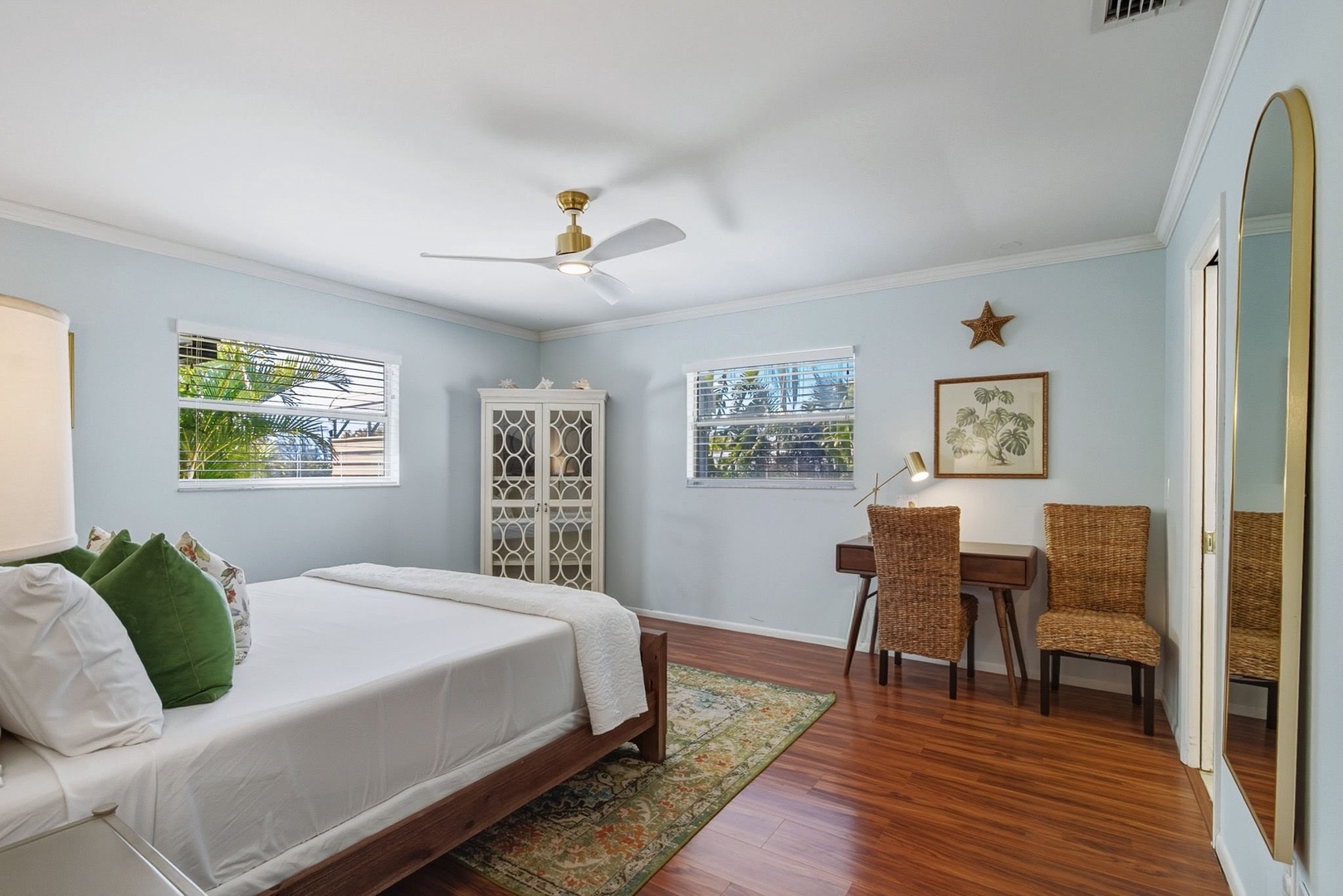 Drift off in your serene bedroom with calming blue walls, rich hardwood floors, and tropical views through your windows.