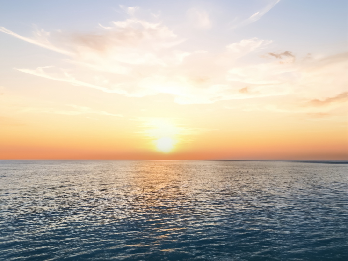 A breathtaking sunset paints the sky in golden hues over calm ocean waters, creating a peaceful seaside ambiance.