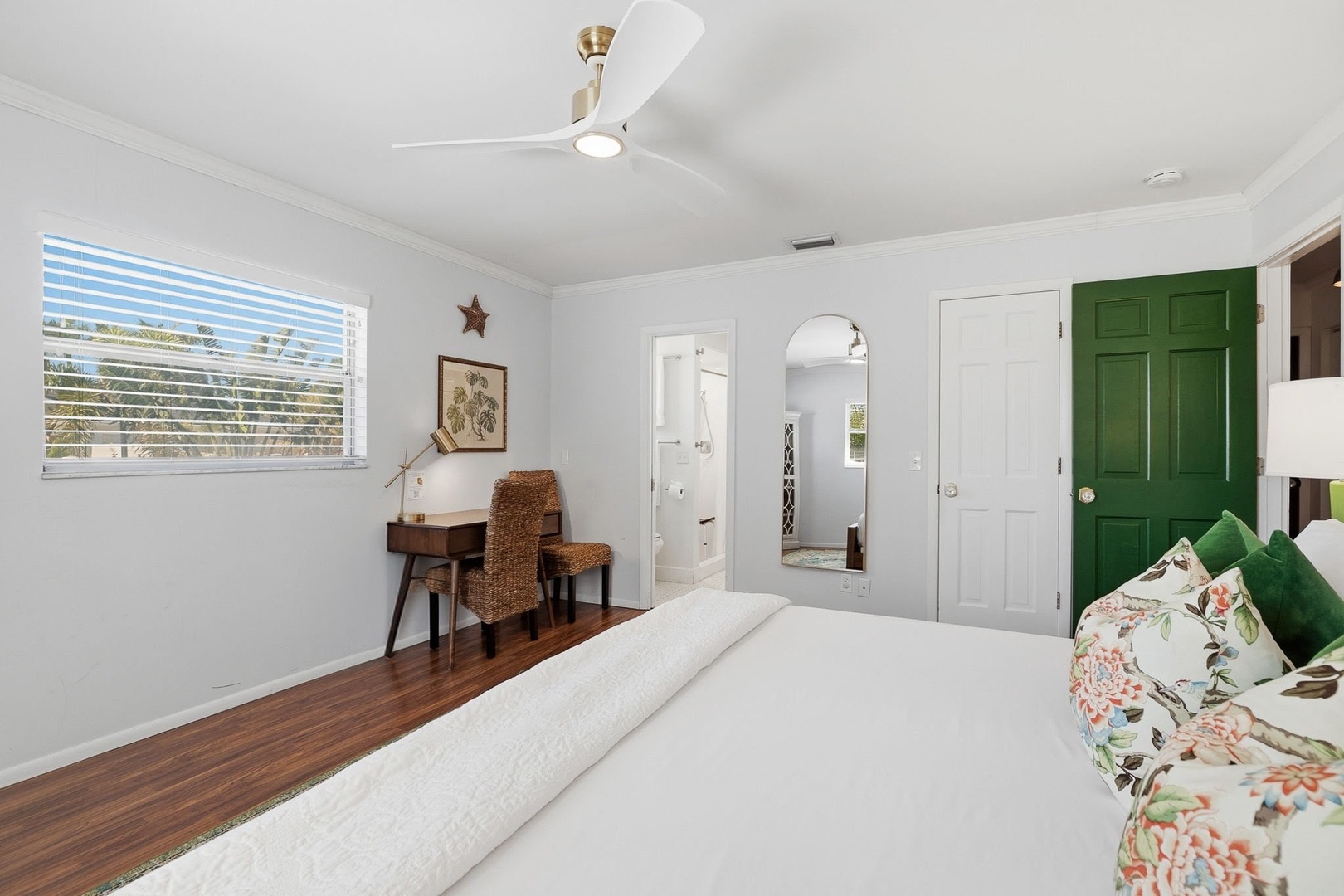 Unwind in your bright bedroom featuring crisp white linens, vibrant green accents, and a cozy workspace by the window.