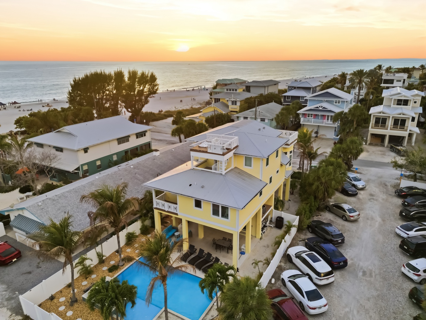Beachfront vacation rental with pool and parking just steps from sandy shores at sunset.