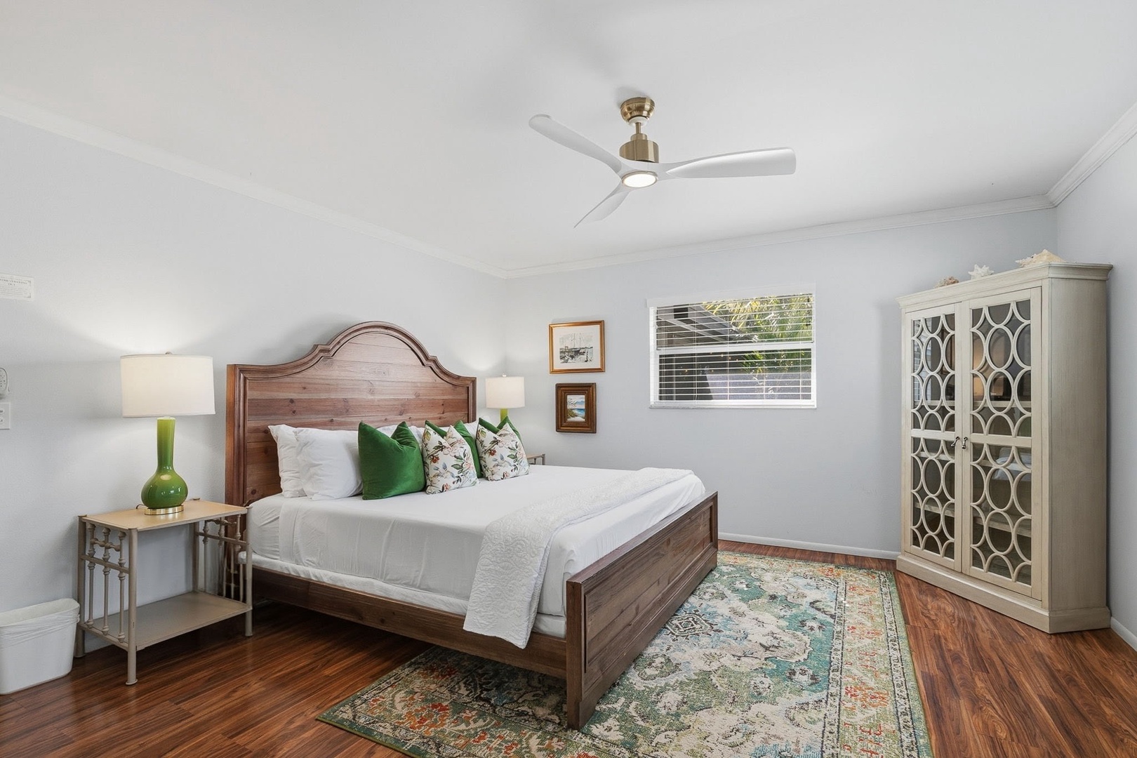 Sink into crisp linens and colorful pillows in your serene bedroom, where warm wood floors and gentle ceiling fan breezes create perfect comfort.