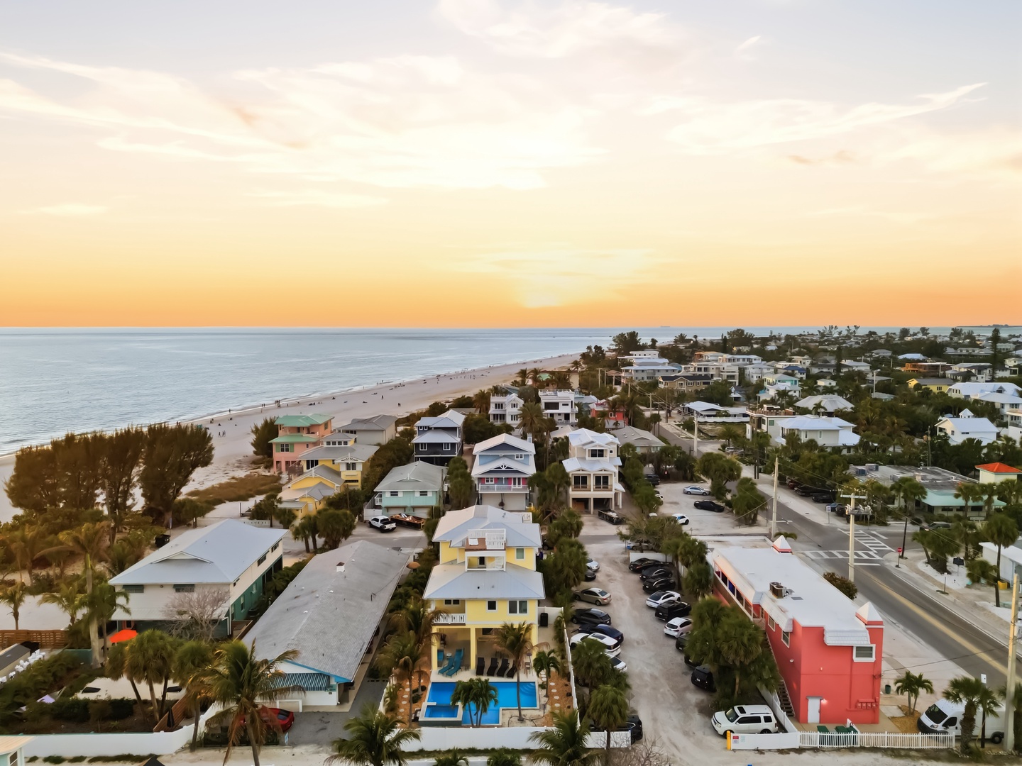 Beachfront community at golden hour with pristine sandy shores stretching along turquoise waters.