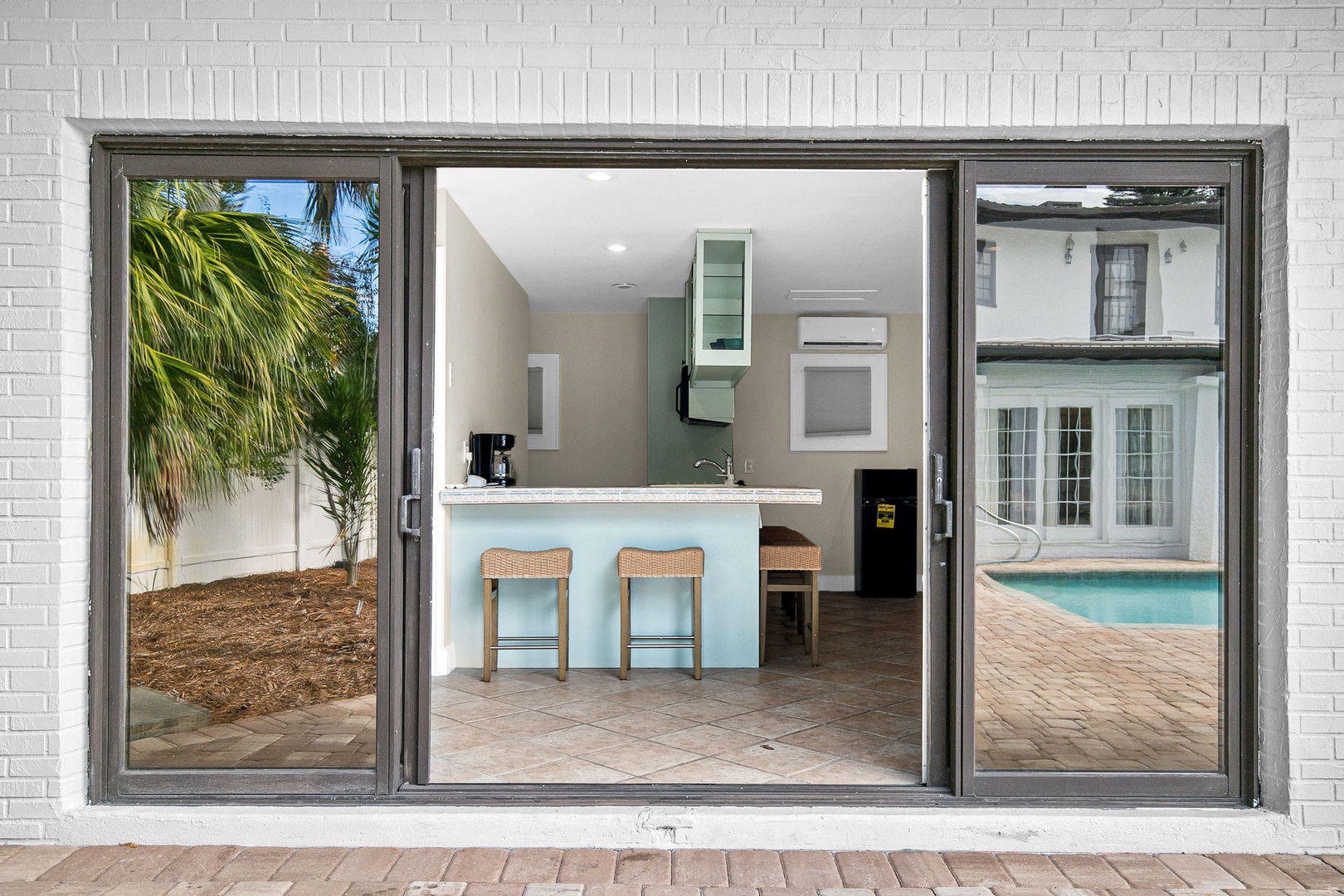 Step into your modern kitchen with sleek countertops and bar seating, perfectly positioned between tropical gardens and sparkling pool views.