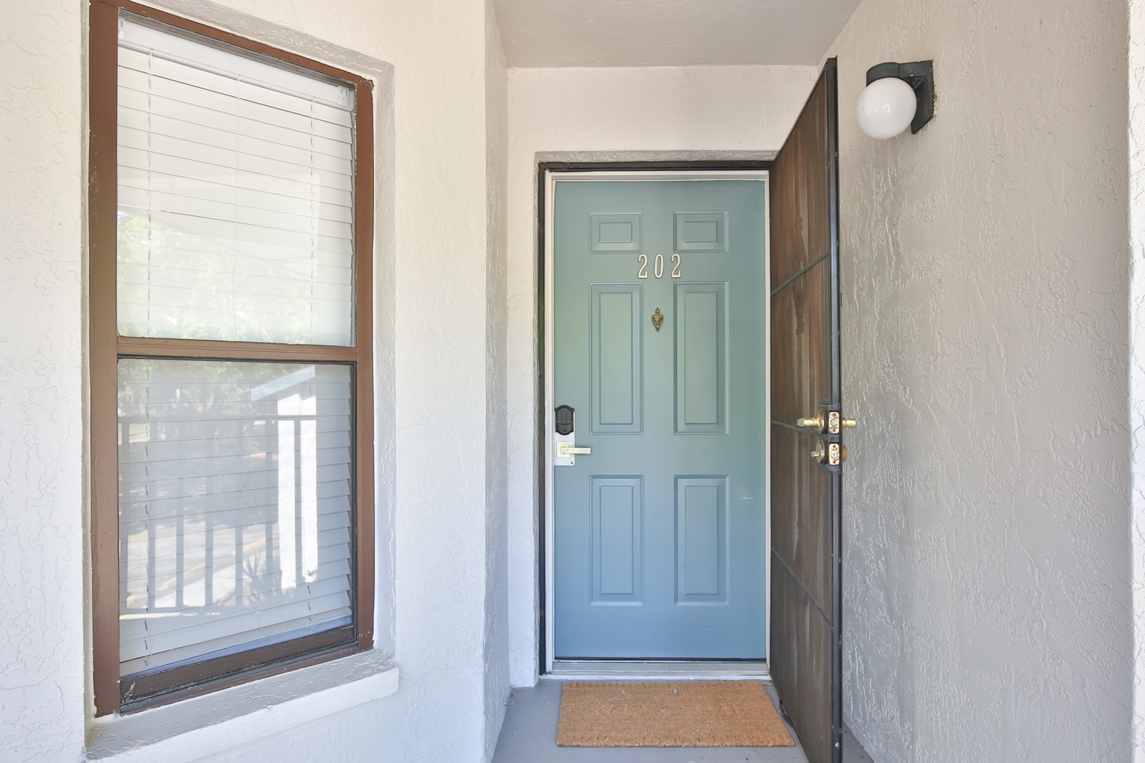 The welcoming entrance to unit 202 features a charming blue door and warm lighting for your arrival.
