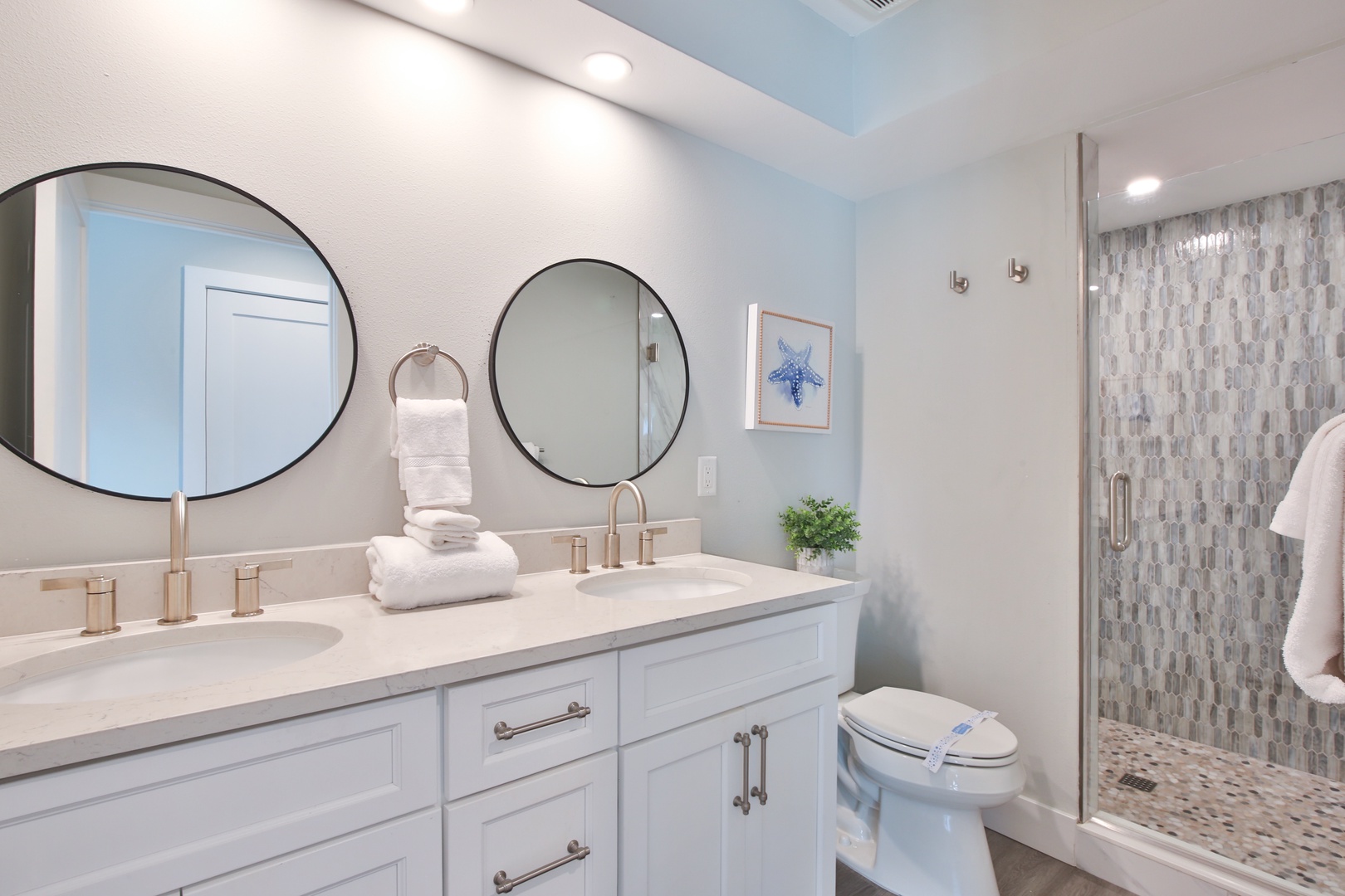Indulge in your private spa-like bathroom featuring dual vanities, elegant gold fixtures, and a stunning tiled shower for ultimate relaxation.