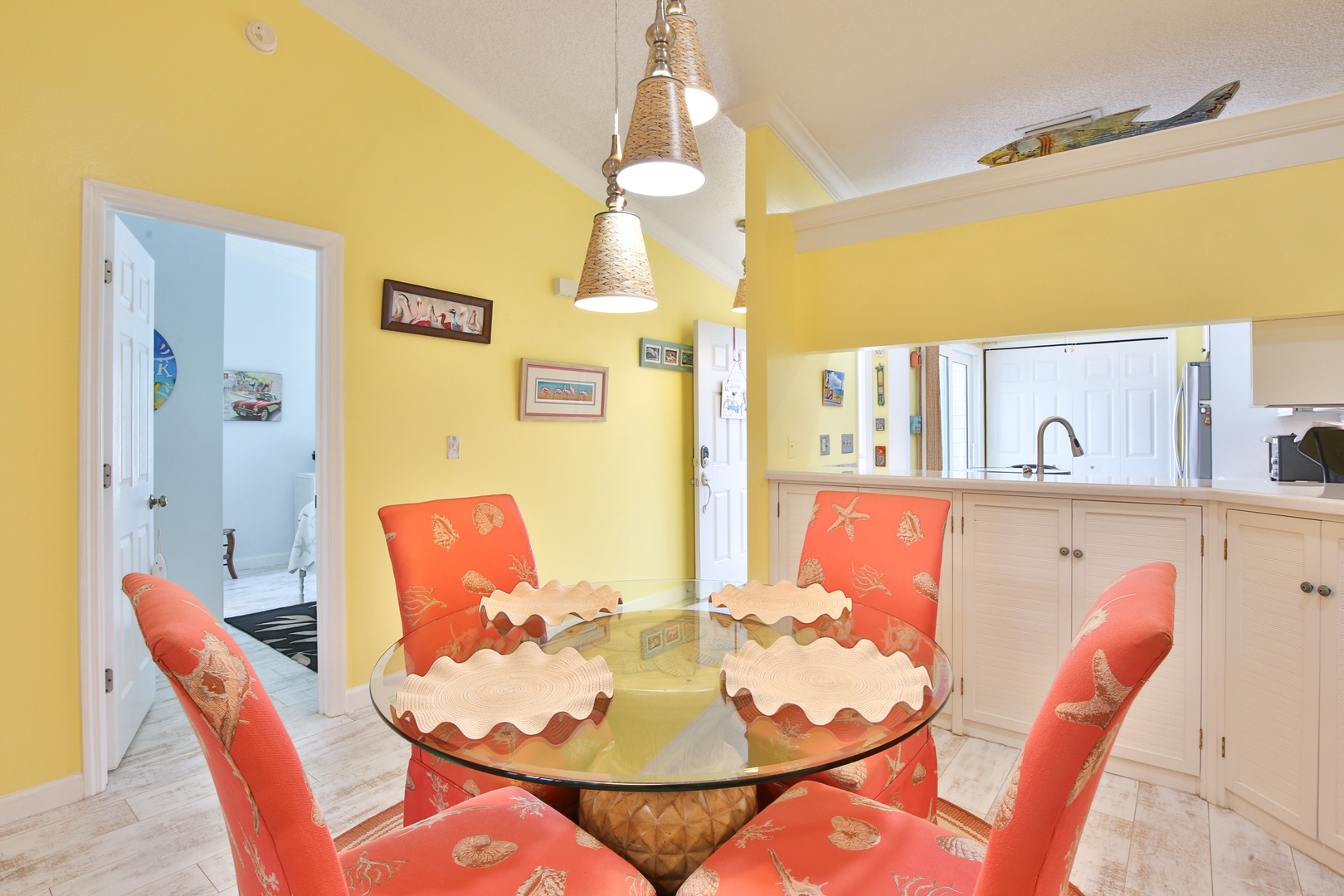 Gather around this charming glass-top table with tropical-themed seating, where the bright, coastal-inspired space invites you to share meals and make memories together.