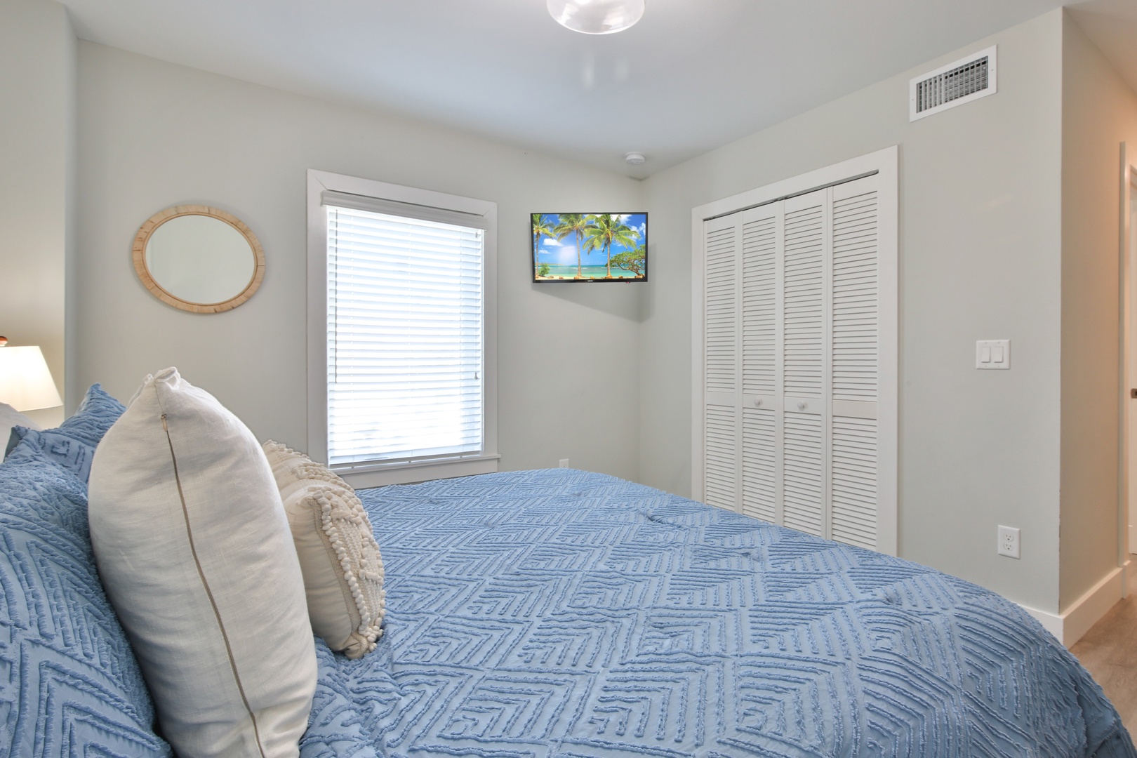 Drift off in comfort with soft blue linens, natural light, and tropical wall art creating your perfect retreat.