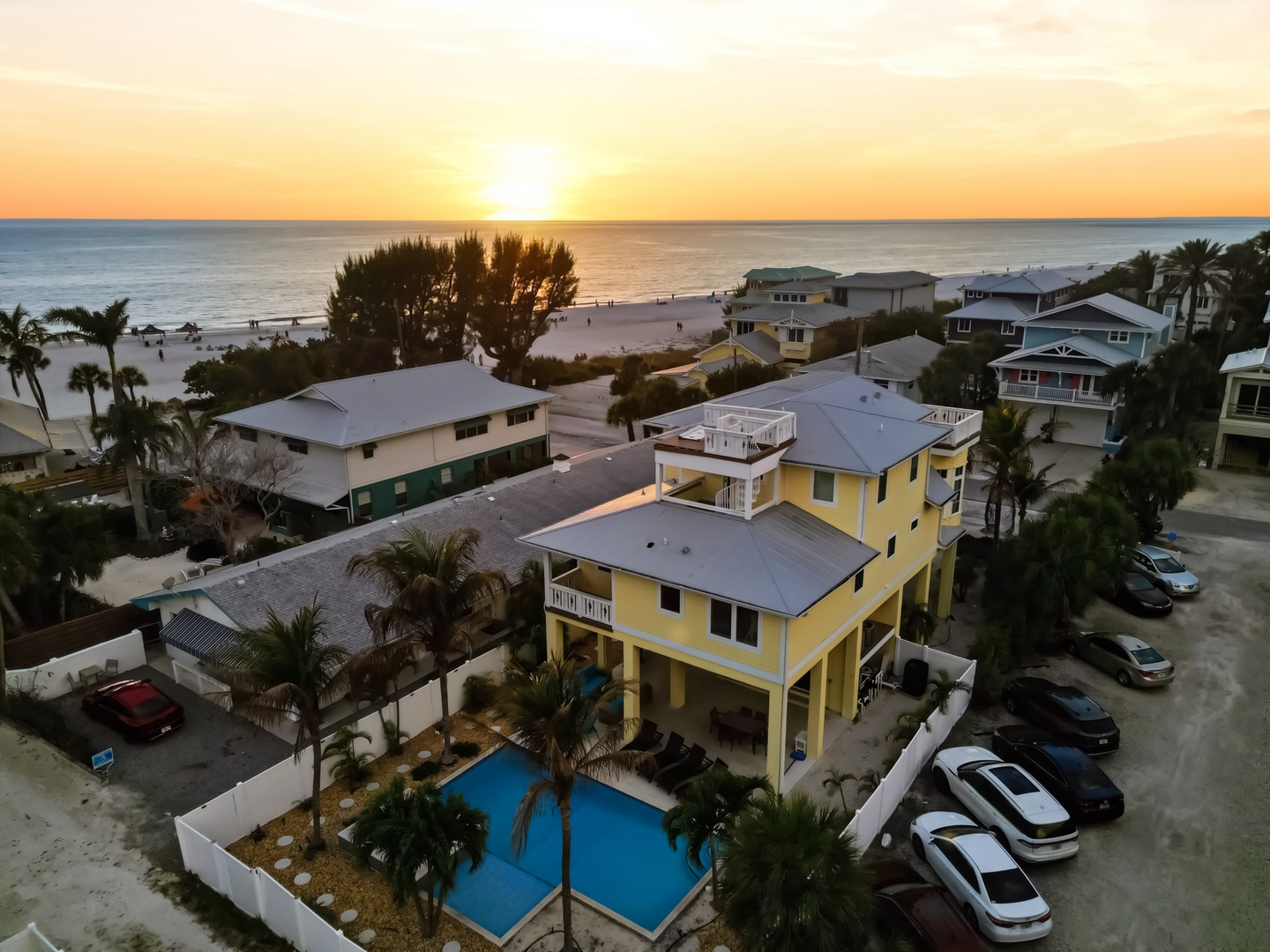 Beachfront paradise showcases colorful coastal homes and pristine sandy shores during golden sunset hour.