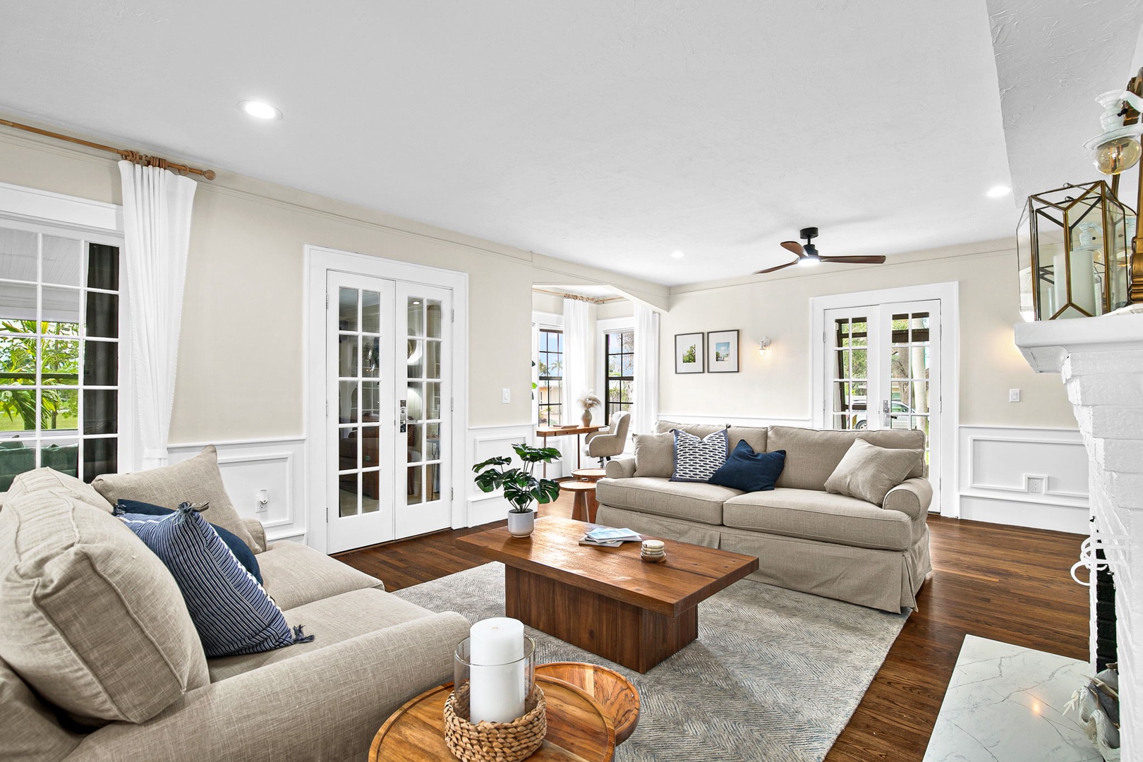 Sink into plush sofas in your elegant living space with rich hardwood floors and natural light streaming through French doors.