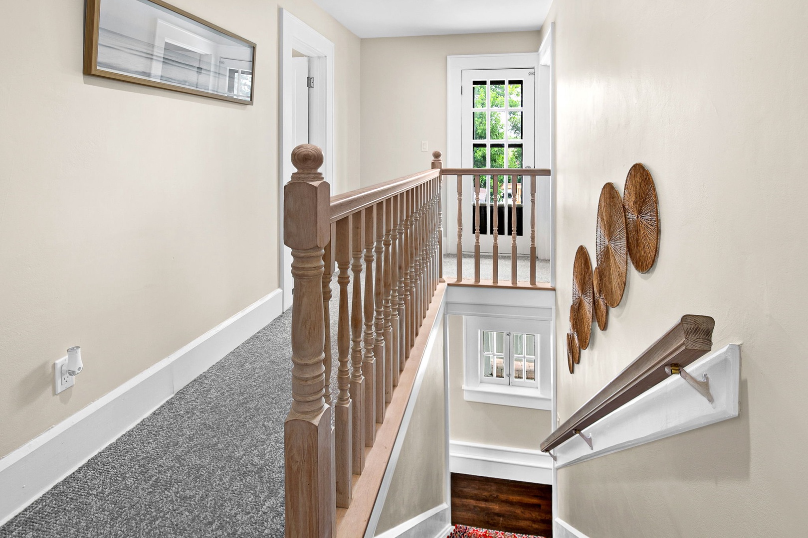 Your upstairs hallway feels bright and welcoming with soft carpet underfoot and charming woven basket art adorning the walls.