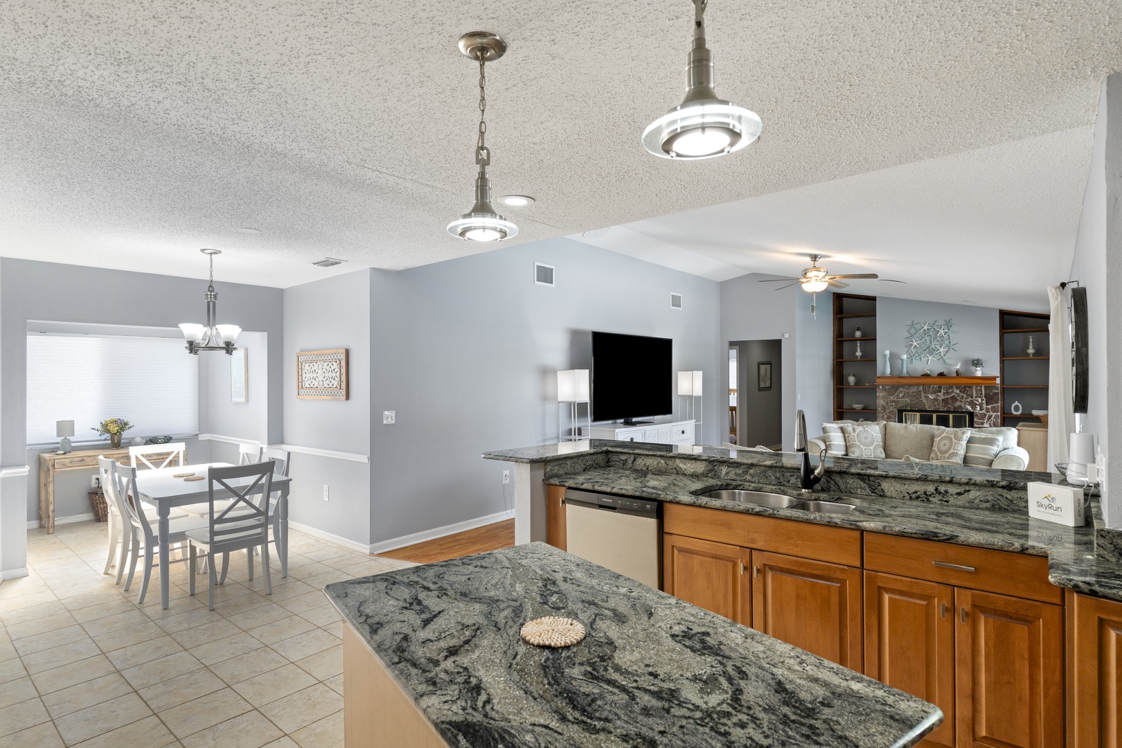 Gather around this open-concept kitchen and living area where you can cook, dine, and relax together. Stunning granite countertops and warm wood cabinetry invite you to create memorable meals.
