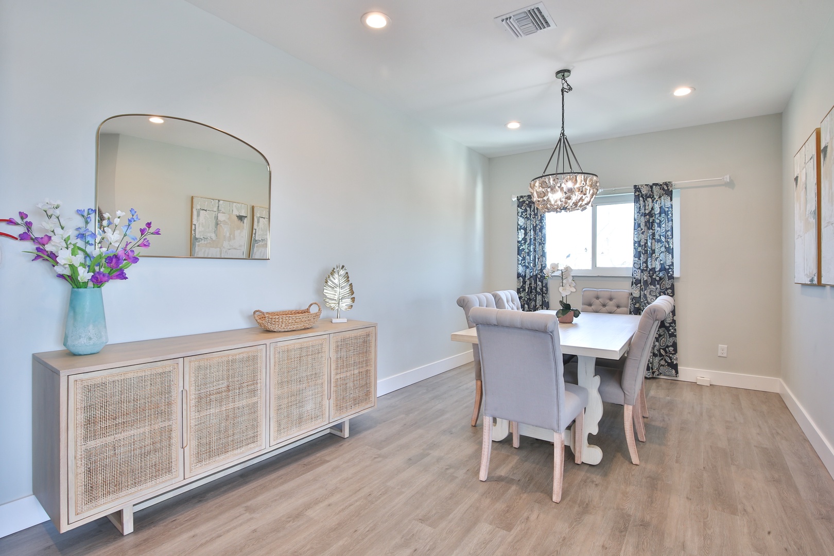 Gather around your elegant dining table beneath a sparkling chandelier, where memorable meals await in this bright, beautifully appointed space.