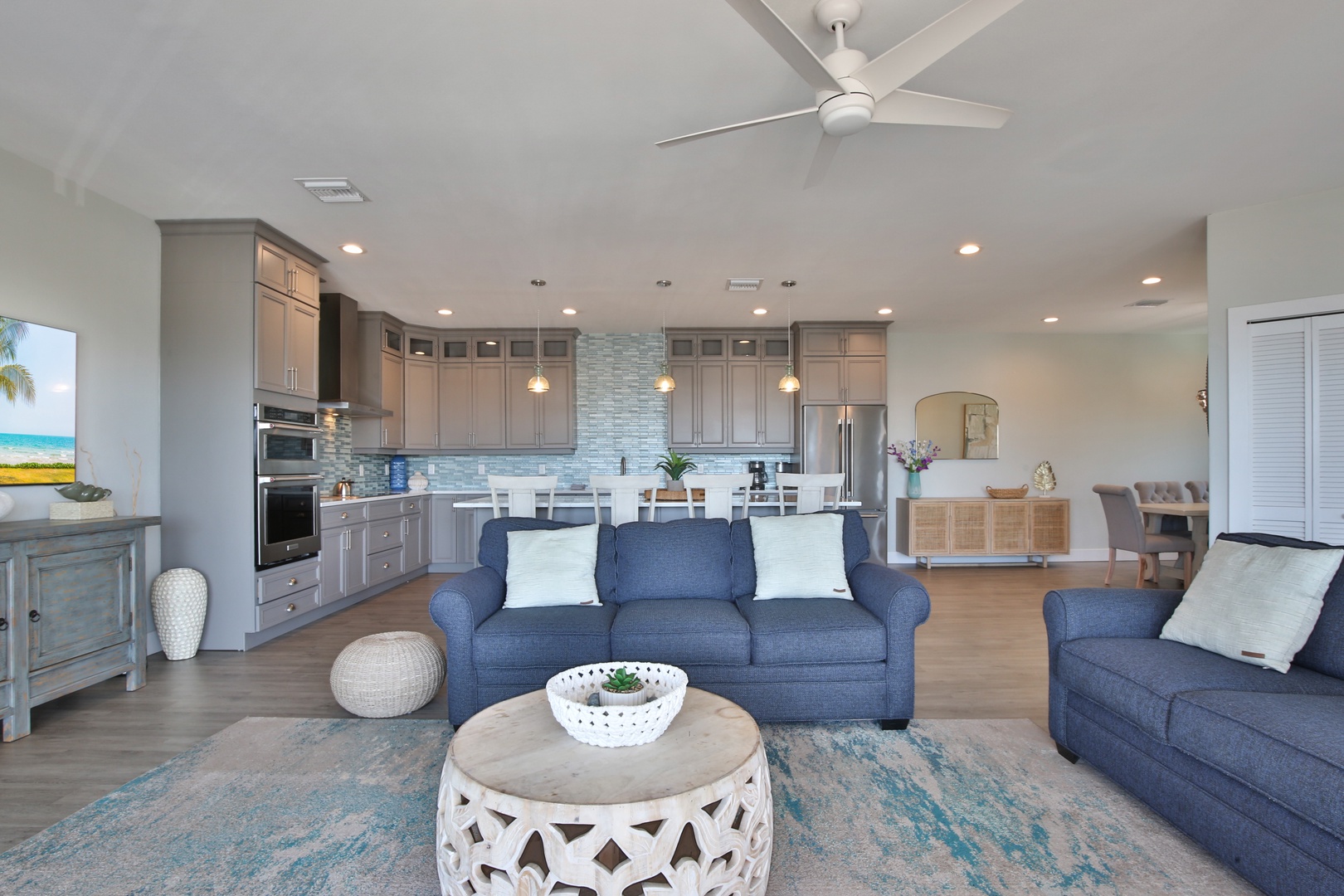 Relax in your spacious open-concept living area where coastal blues meet modern comfort. The kitchen's sleek design flows seamlessly into your lounge space.