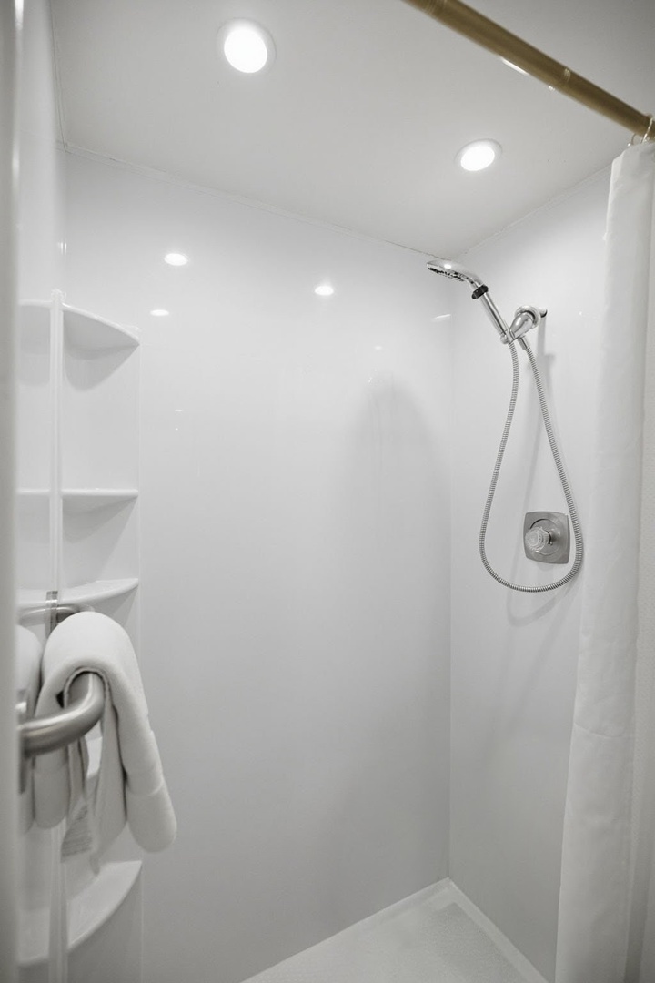 Step into your private, modern shower featuring bright LED lighting, handheld sprayer, and accessibility grab bars for comfort.