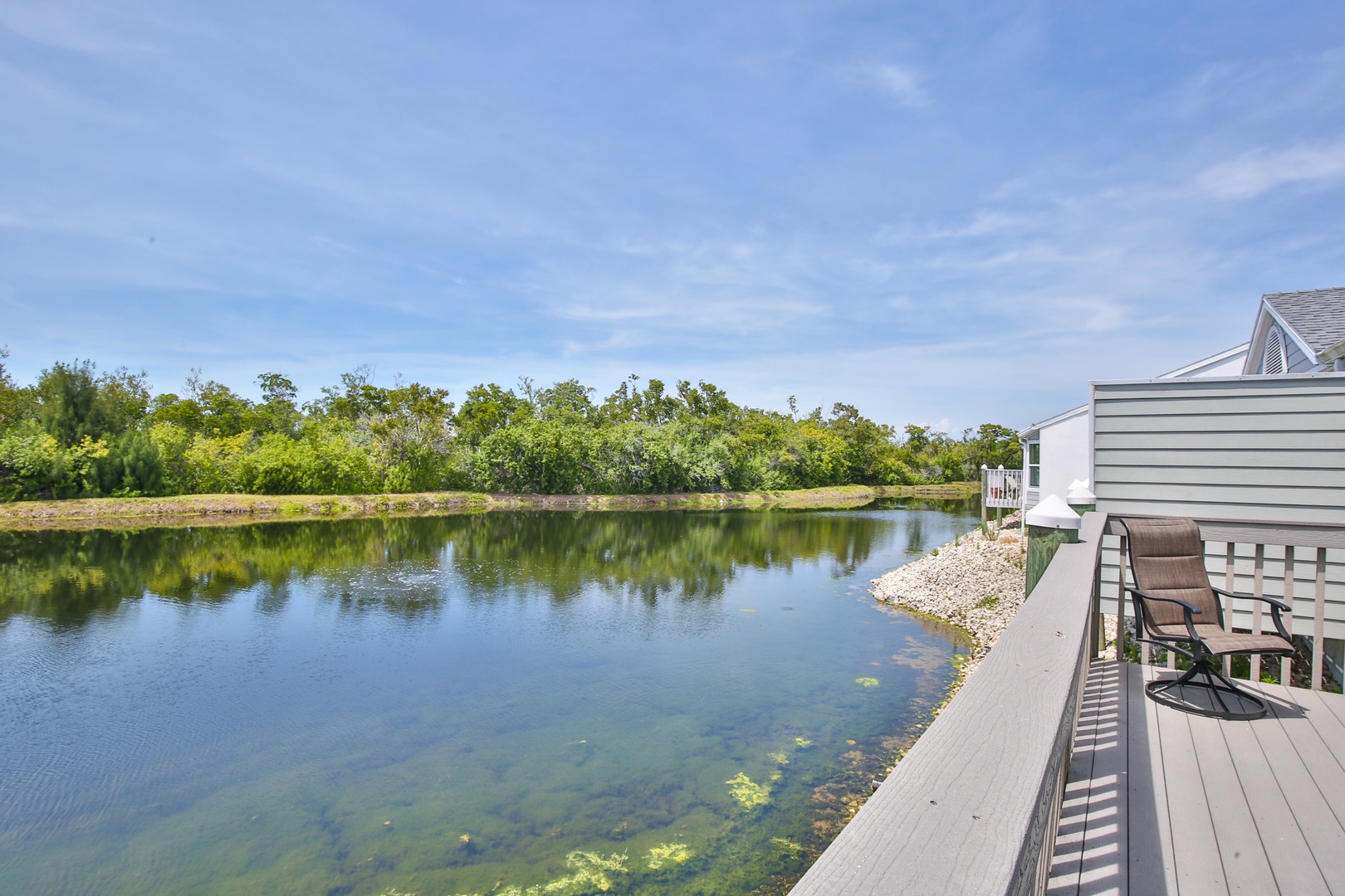 This private waterfront deck showcases a tranquil pond framed by lush greenery, offering a peaceful setting for morning coffee or afternoon relaxation.