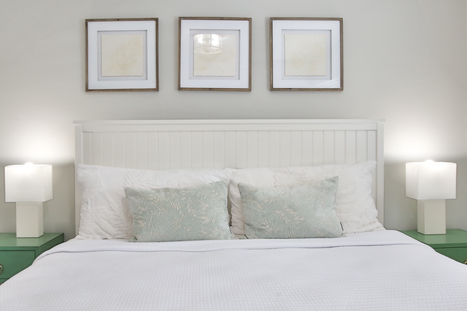 Sink into crisp white linens and plush pillows in your peaceful bedroom, where elegant coastal touches and warm lighting create the perfect retreat.